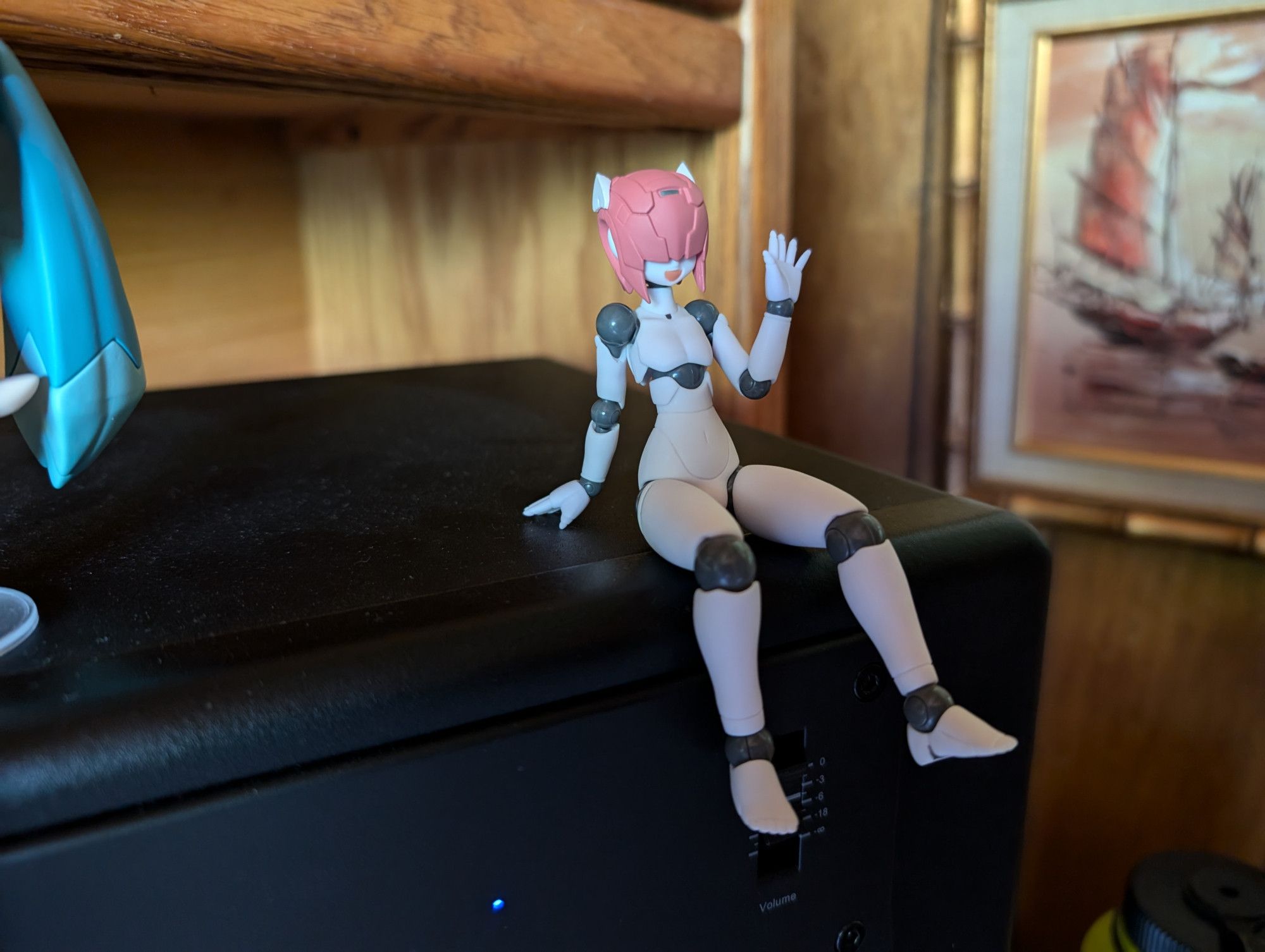 A photo of my Polynian Shamrock pose-able anime figure. He is sitting on top of my right studio monitor speaker.