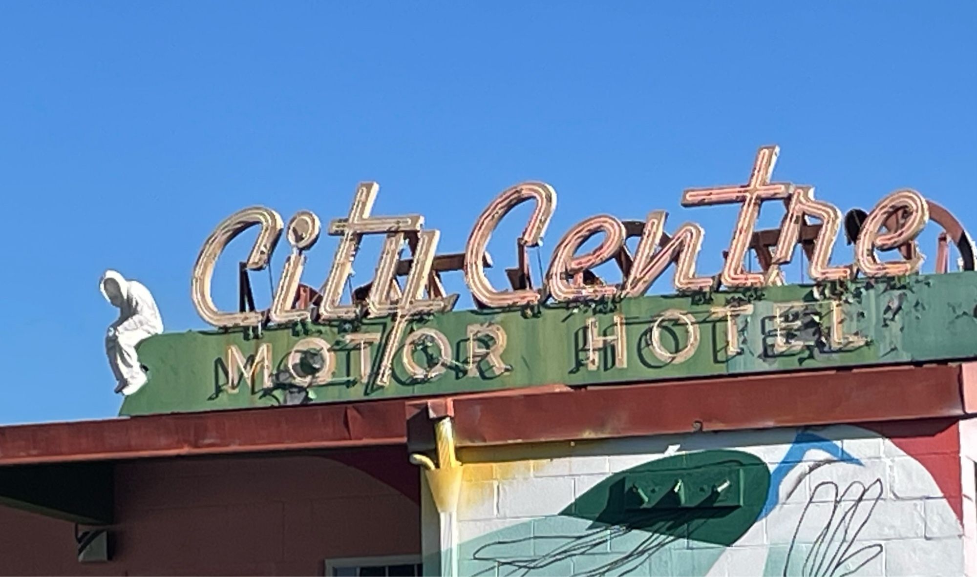 A pale shrouded sculpture sits forlornly on the Artist coop ‘ City Centre Motel’ sign waiting for it to be torn down for condos.