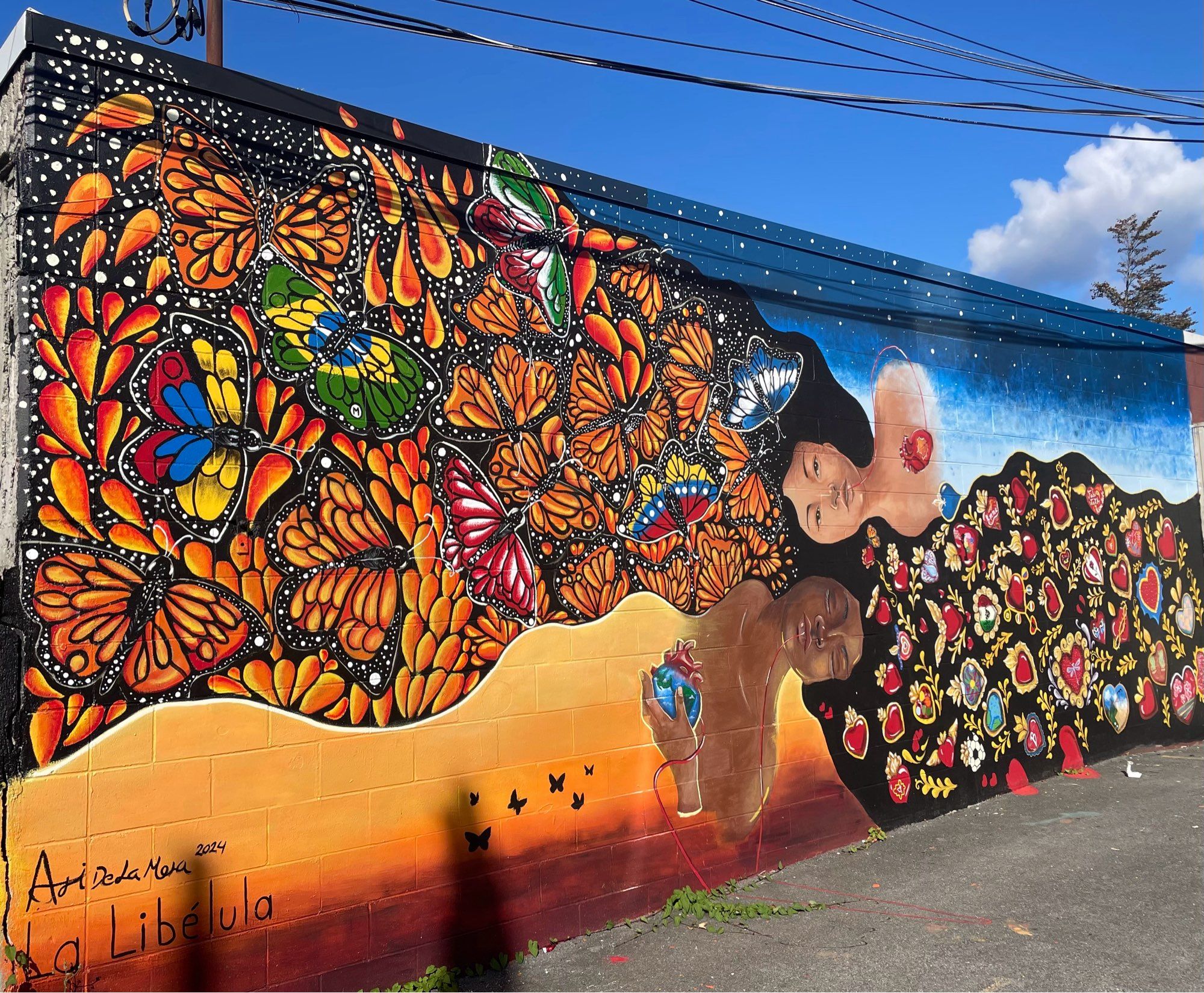 Gorgeous mural with warm colours with woman laying sideways with a burst of butterflies coming out of her hair.