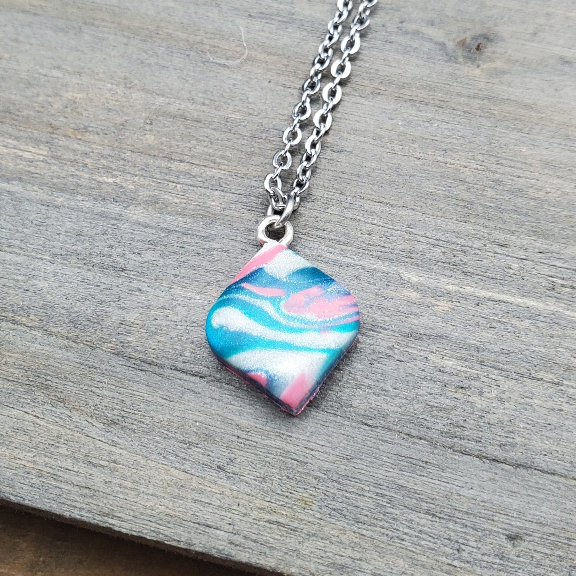 A teeny tiny psychedelic polymer clay pendent on a stainless chain.