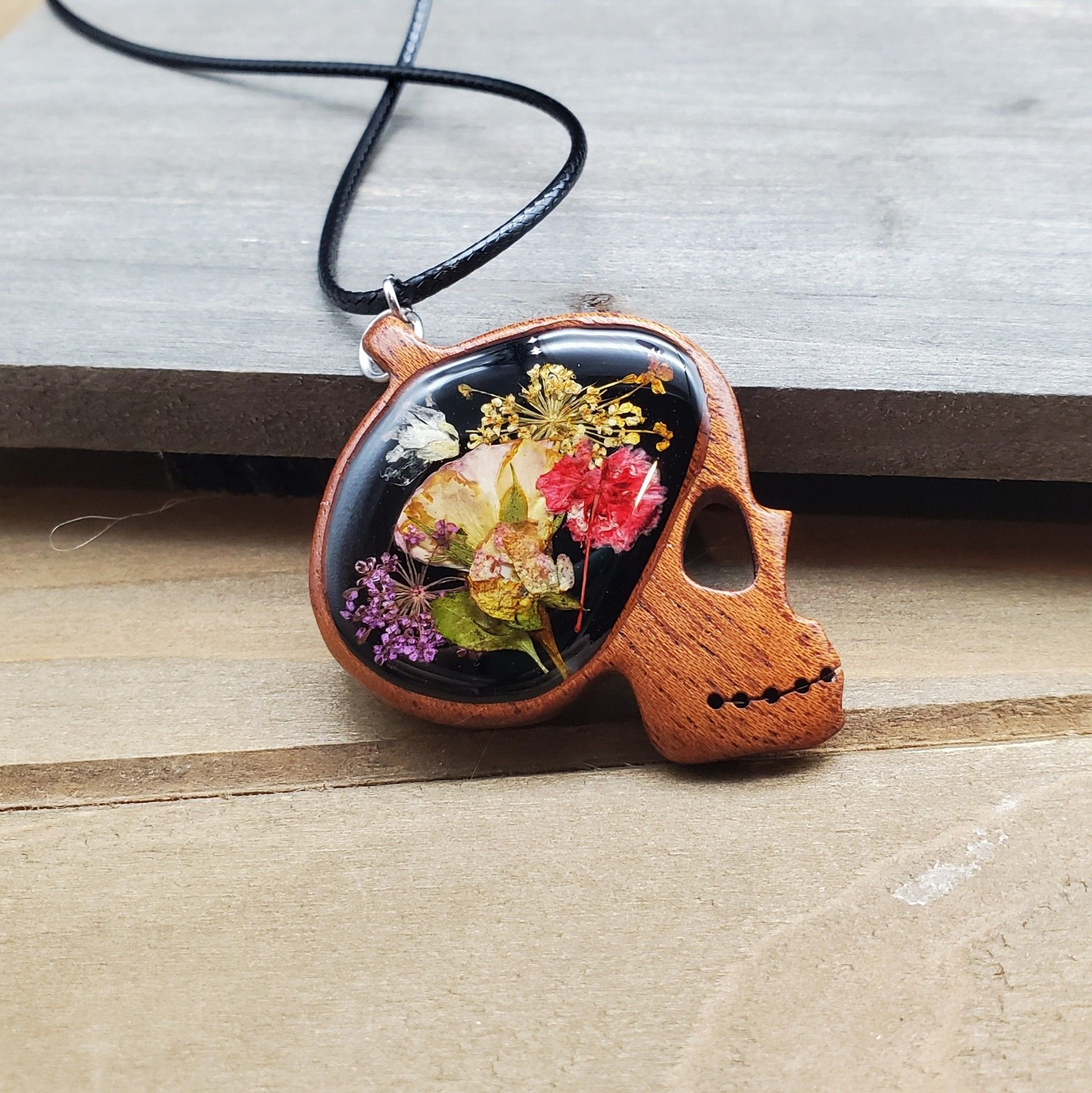 It wooden skull pendant with flowers in resin where the brain should be.