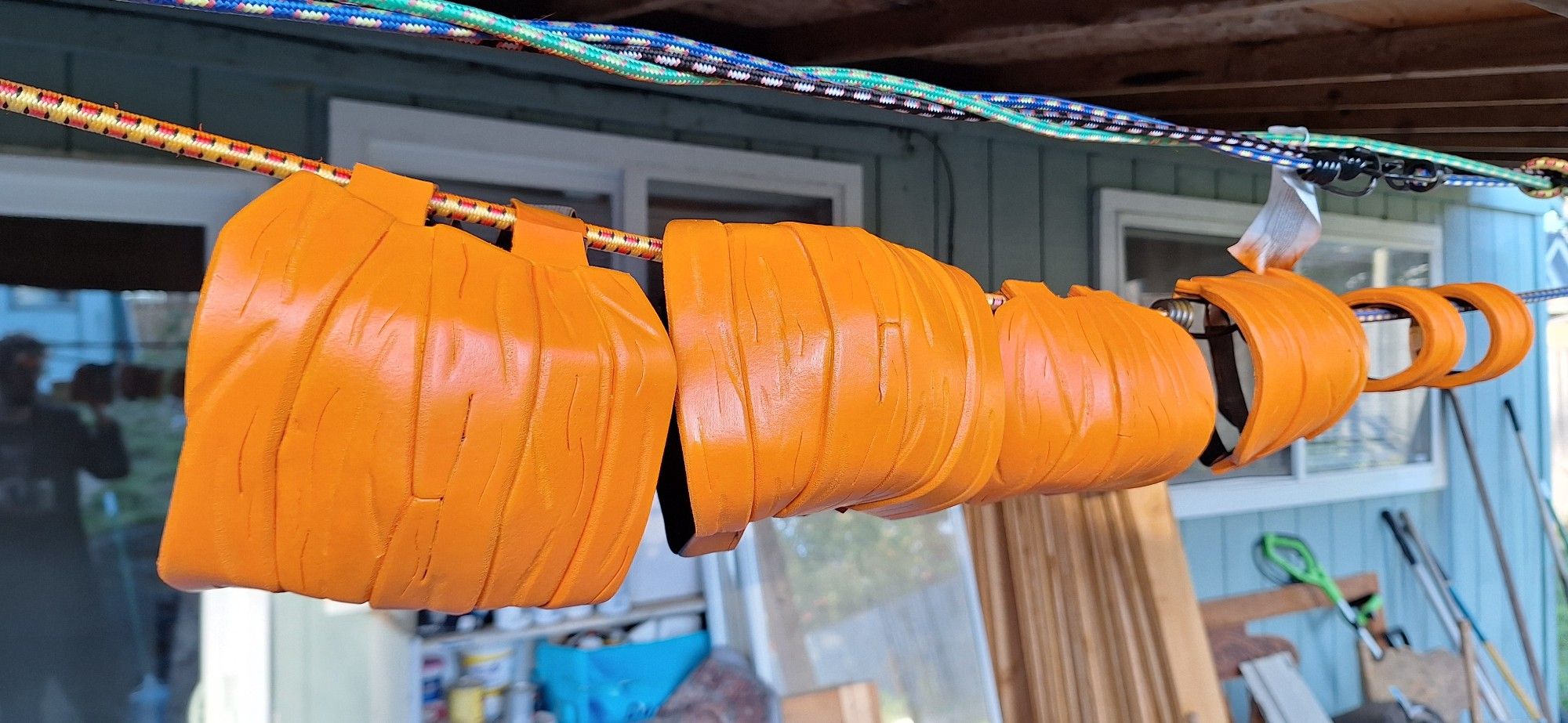 Wristbands, elbow pads, and kneepads along a line of bungee cords, the pumpkin orange paint drying in the sun