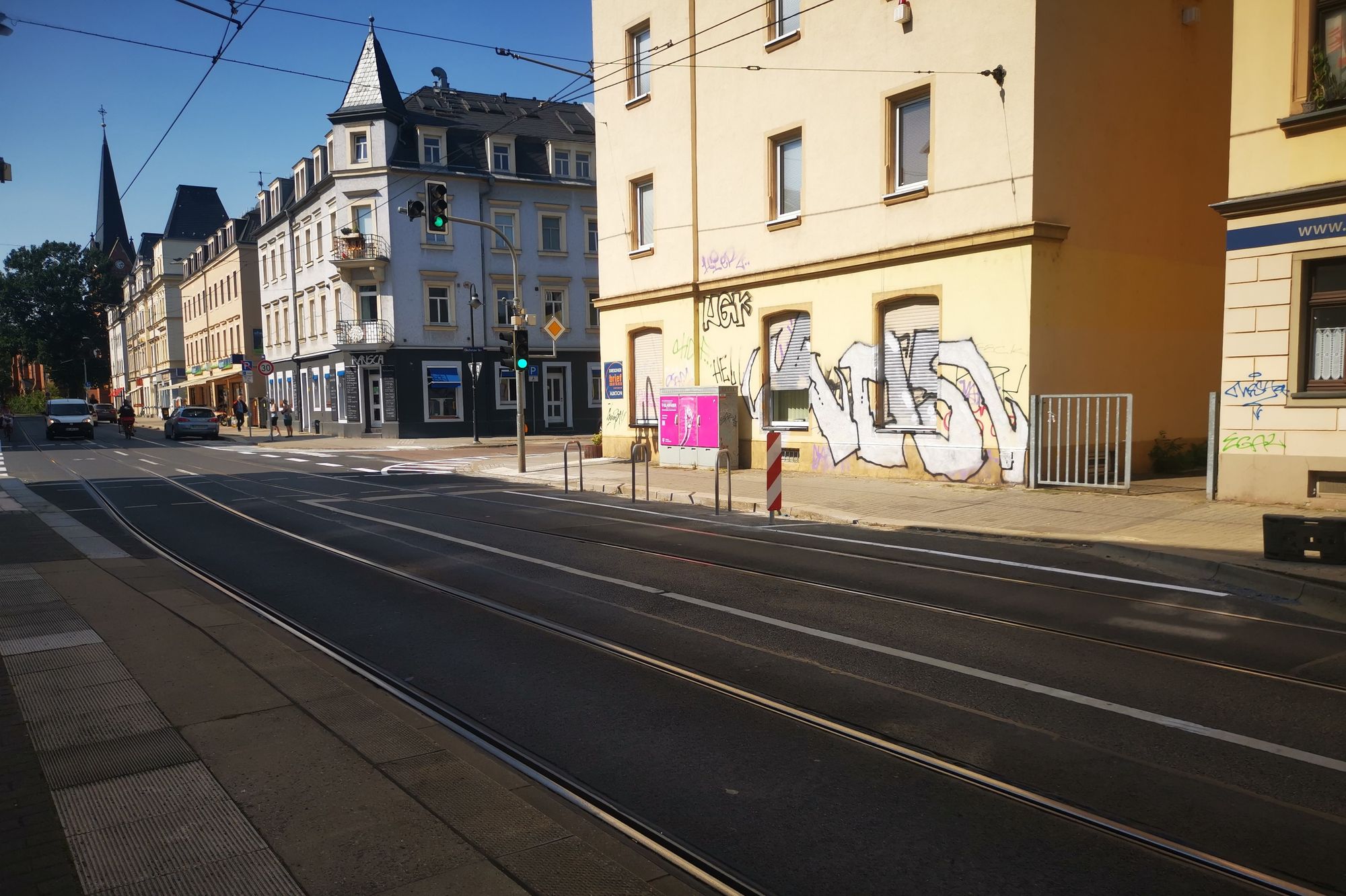 Blick auf eine Fußgängerinnenampel, bei der auf die Fahrbahn davor 3 Fahrradbügel gesetzt wurden. 