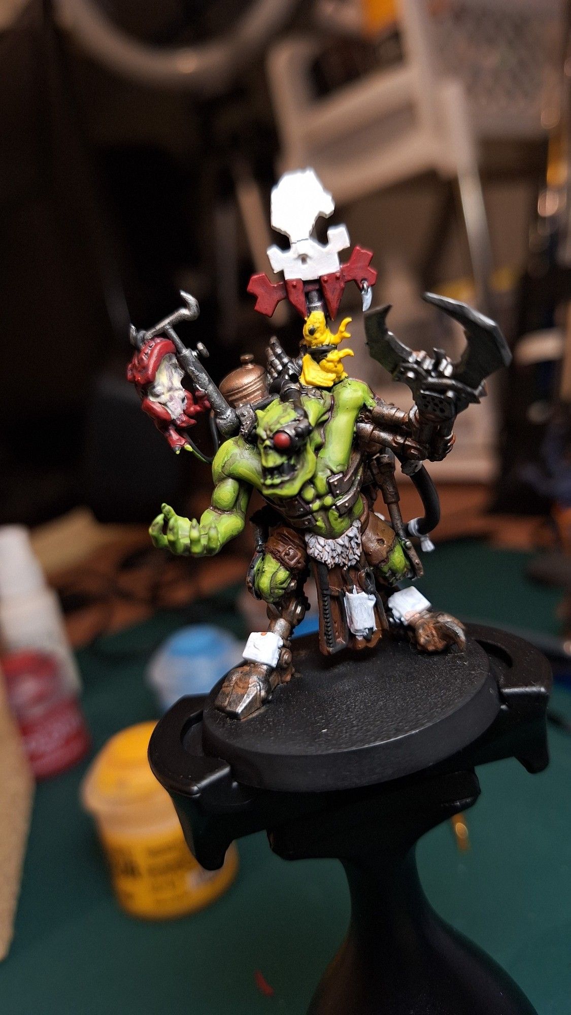 An Ork Painboss miniature. In green, white, and red. It's not finished.