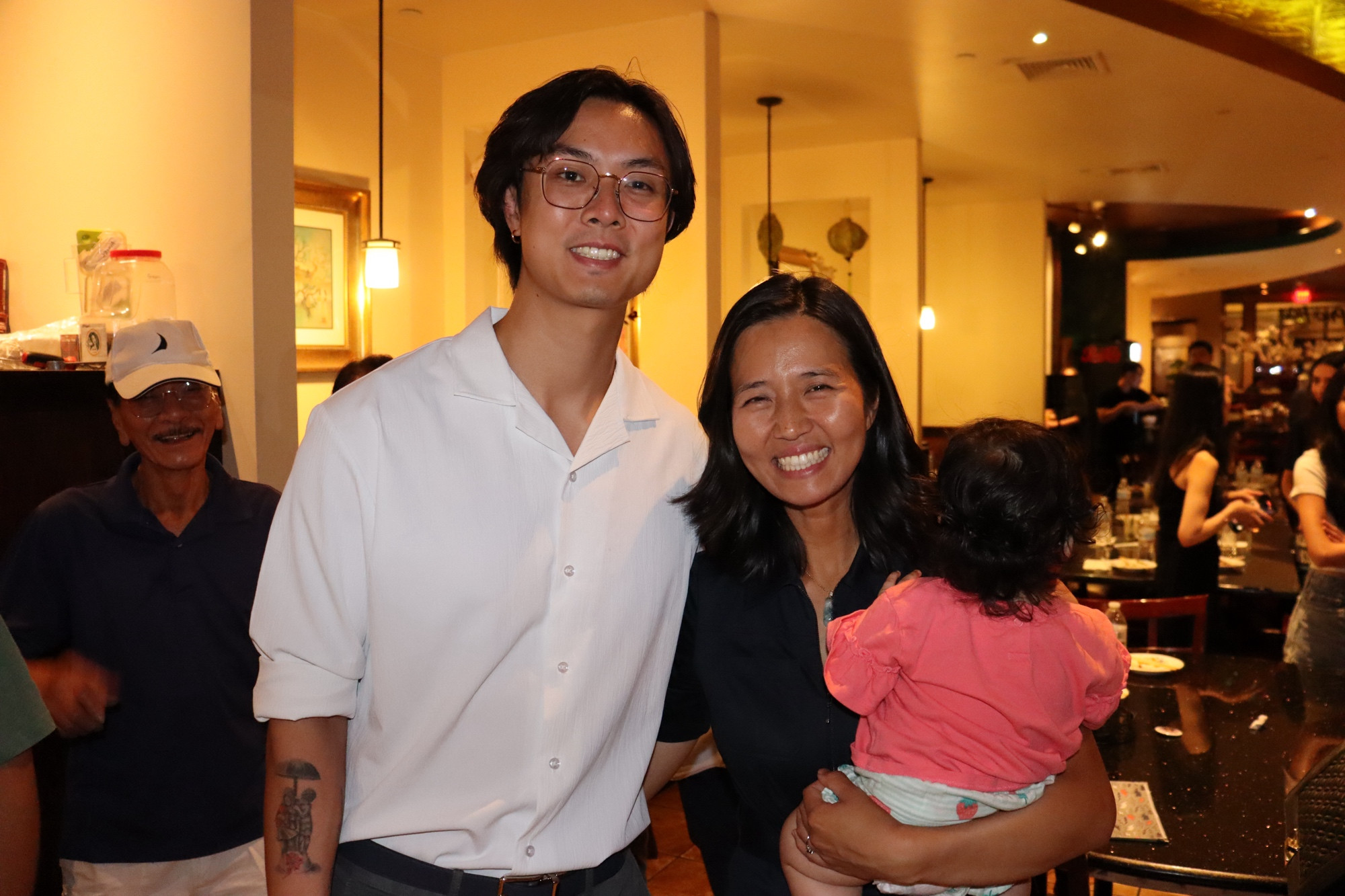 Mayor Wu and Mira pose for a photo in the restaurant with a constituent. 