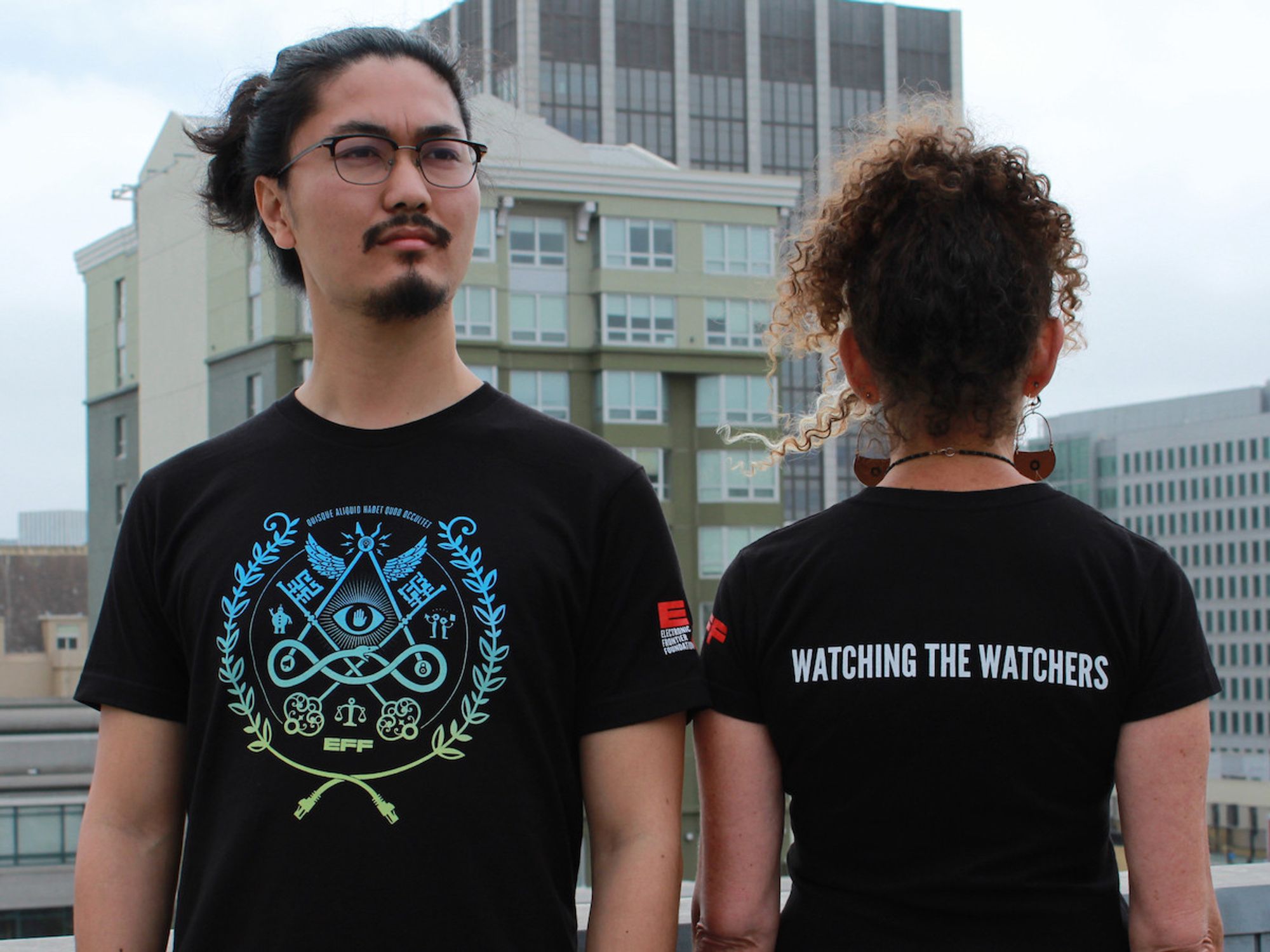 EFF's Watcher's t-shirt. Black t-shirt with "Watching the Watchers" text on the back. Front features a privacy focused design with blue-green gradient.