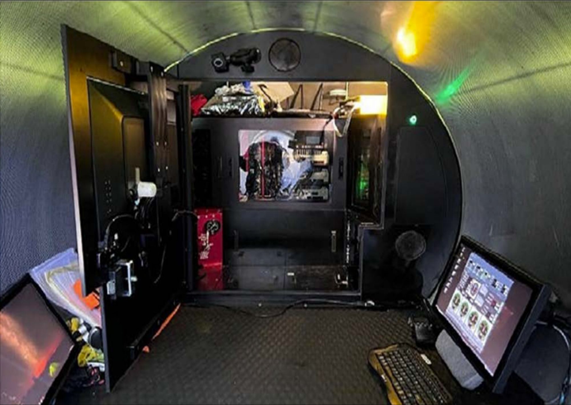 sub interior, with the computer enclosure (clear plastic, almost looking like a gamer PC with a window). in the foreground is an LCD monitor and a cheap keyboard. the access panel for the computers has a large LCD TV mounted to it using a VESA mount