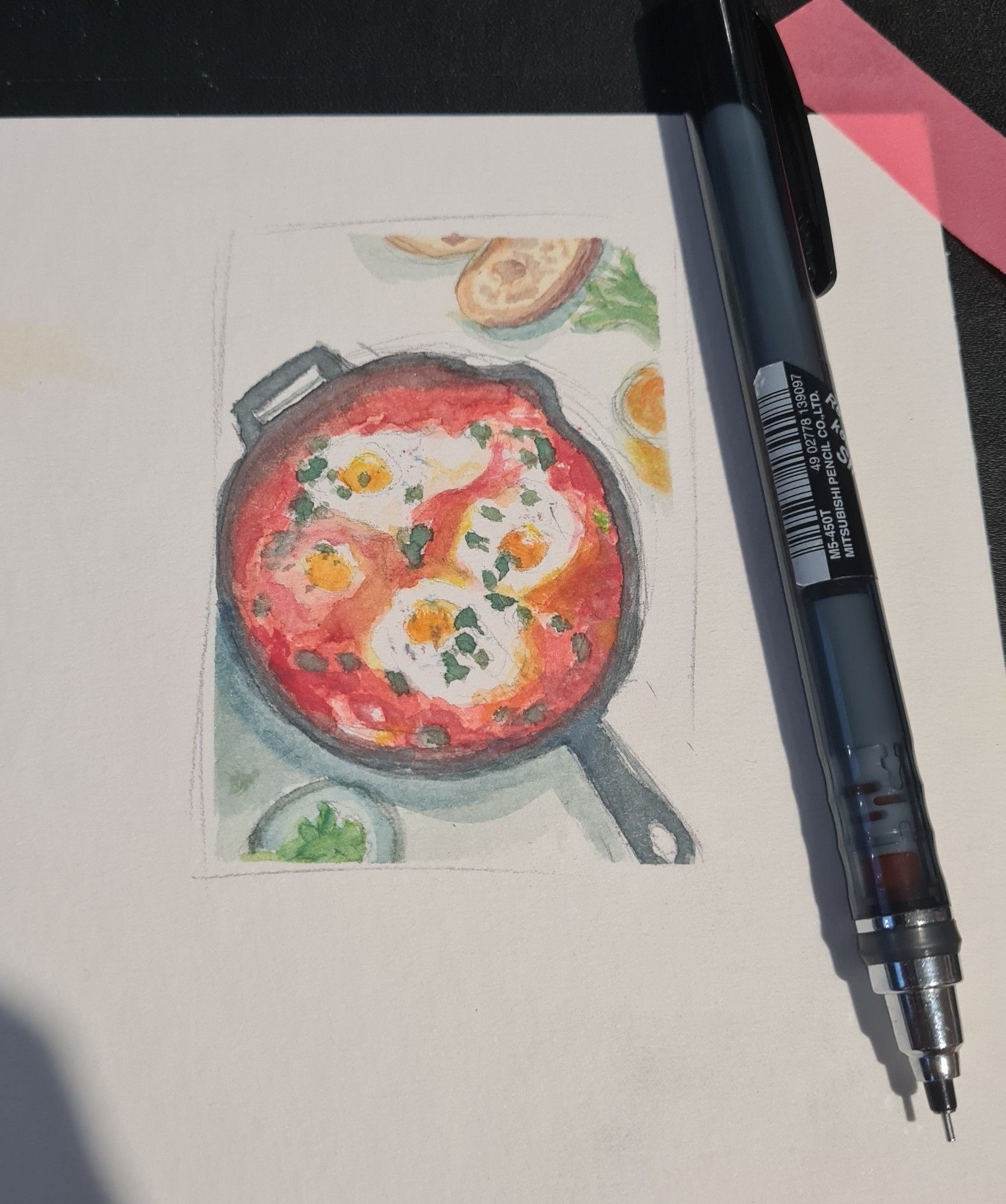 A picture of a watercolor painting. Inside a cast iron, 4 eggs nested in a sea of tomato and bellpepper sauce, with fresh herbs sprinkled on top (it doesn't have cheese tho, don't ask me why)
Next to it is a mechanical pencil, approx. Double the length of the drawing.