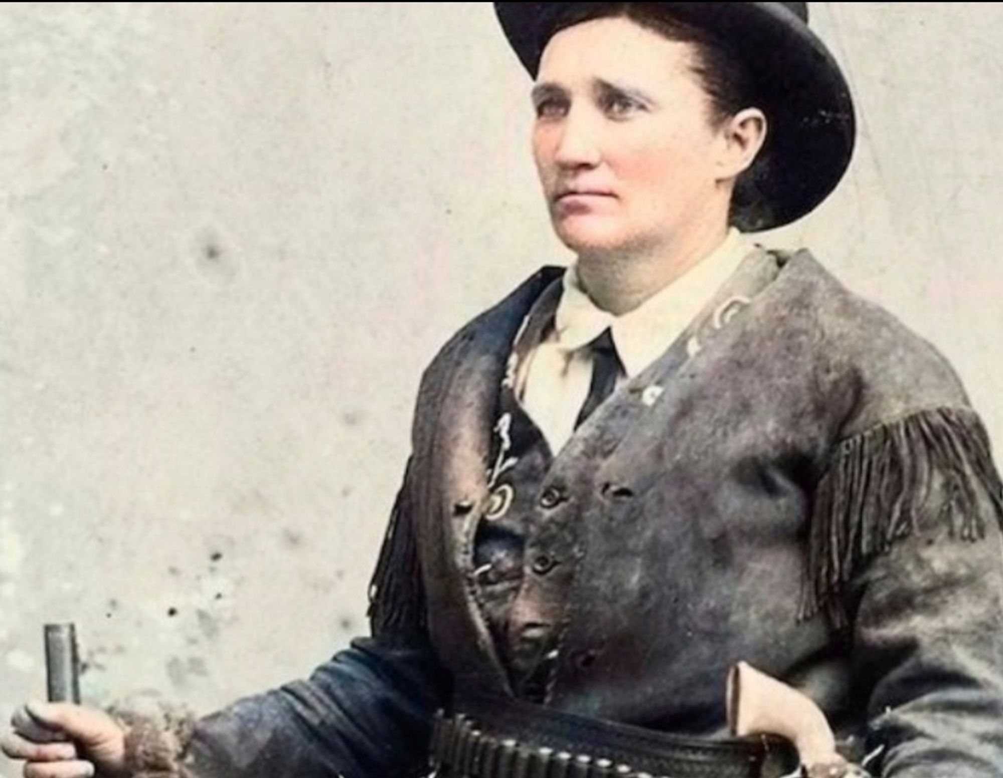 Calamity Jane, Martha Jane Cannary Burke, koloriert, Halbprofil, Hut, Lederjacke rechte Hand mit Gewehrspitze sichtbar, links Pisolenknauf am Nietengürtel