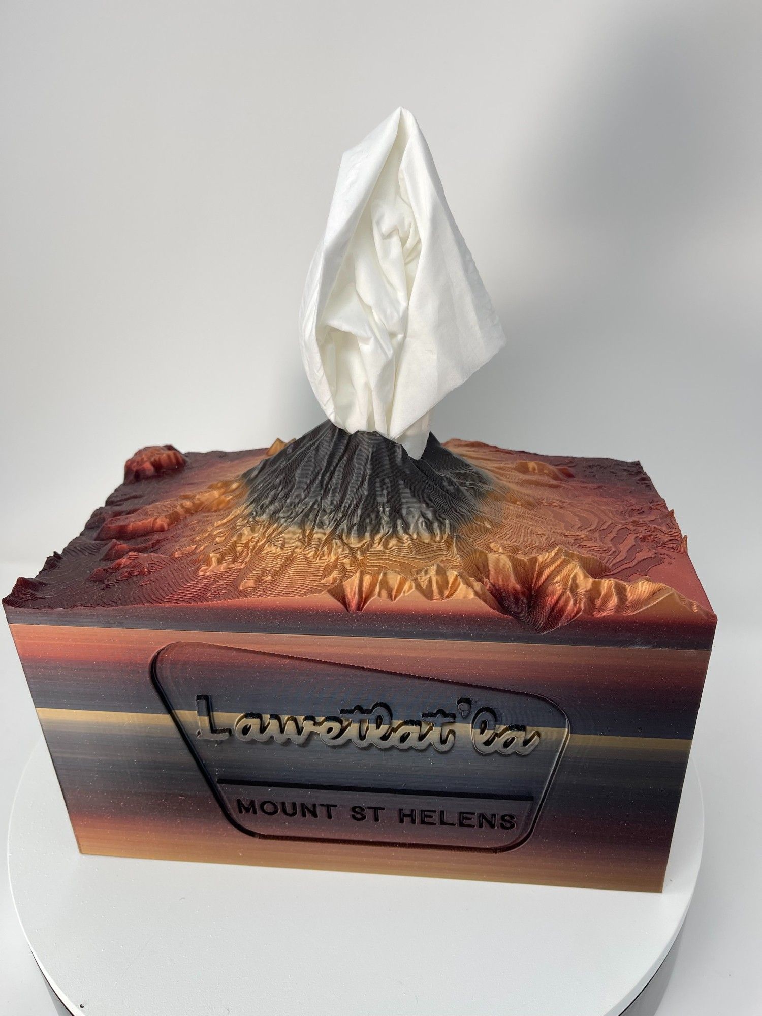 Large tissue box cover in the shape of mt st helens in gold black gradient color.