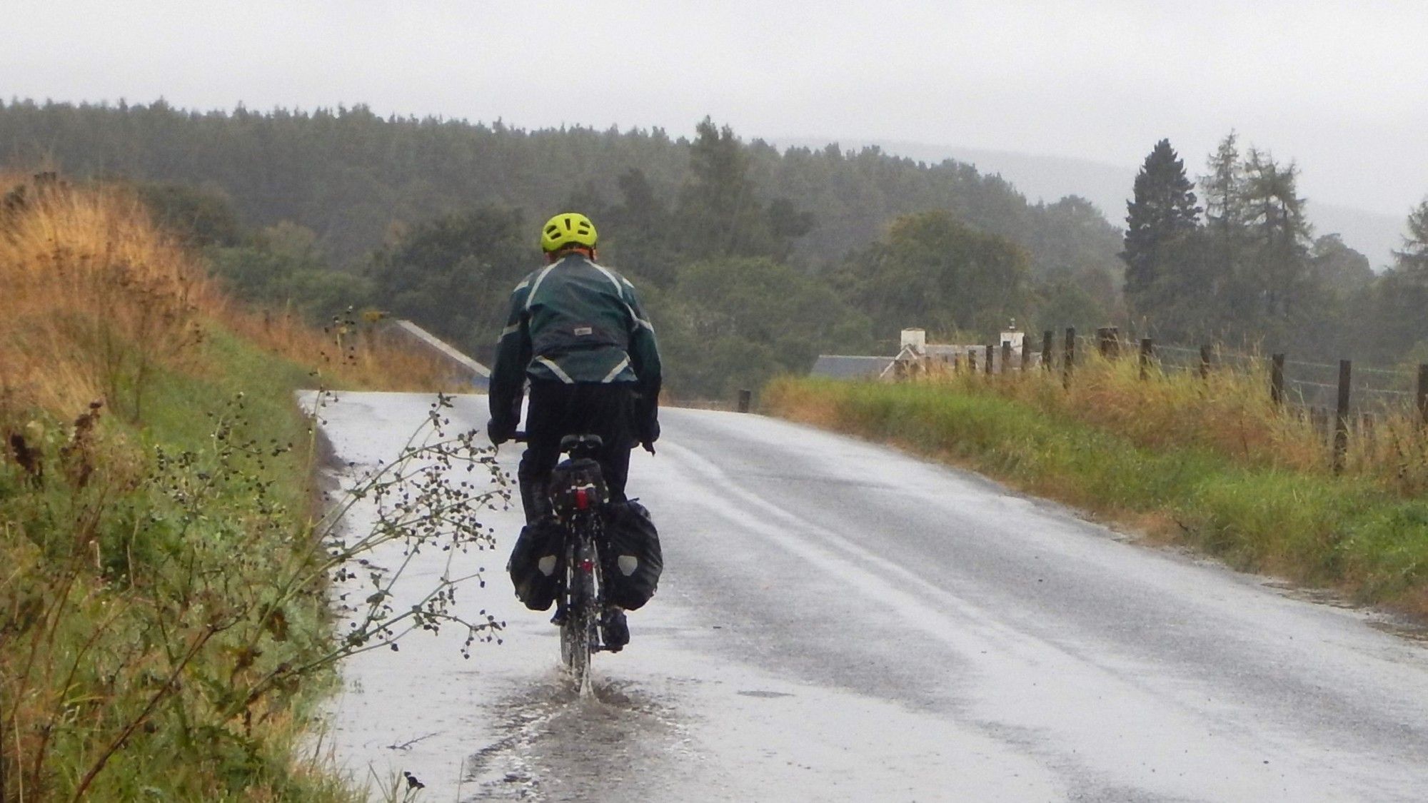 Lone cyclist rolling through a puddle in torrential rain.