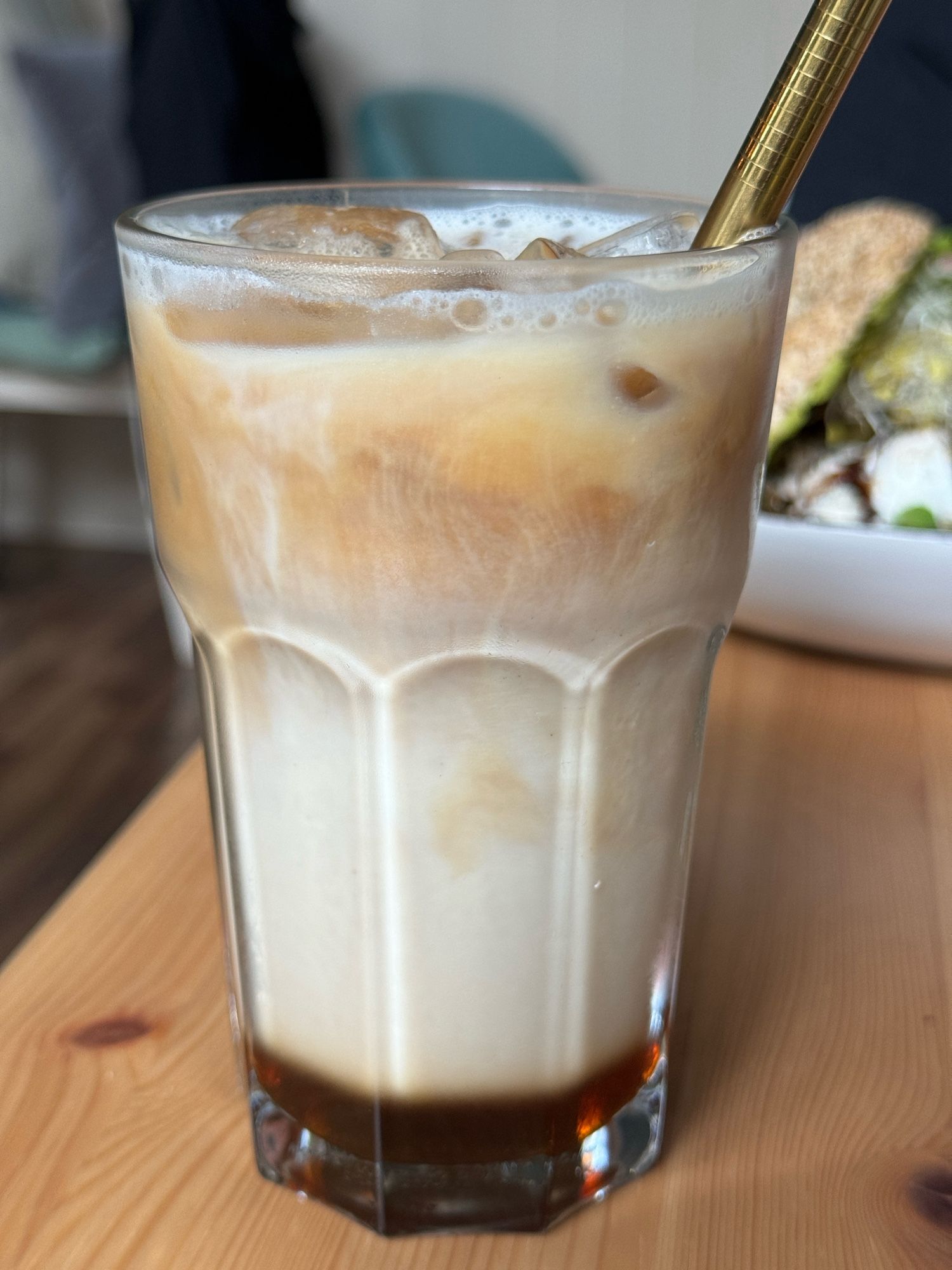 Ein hohes Glas Caramel Macchiato mit Eiswürfeln.