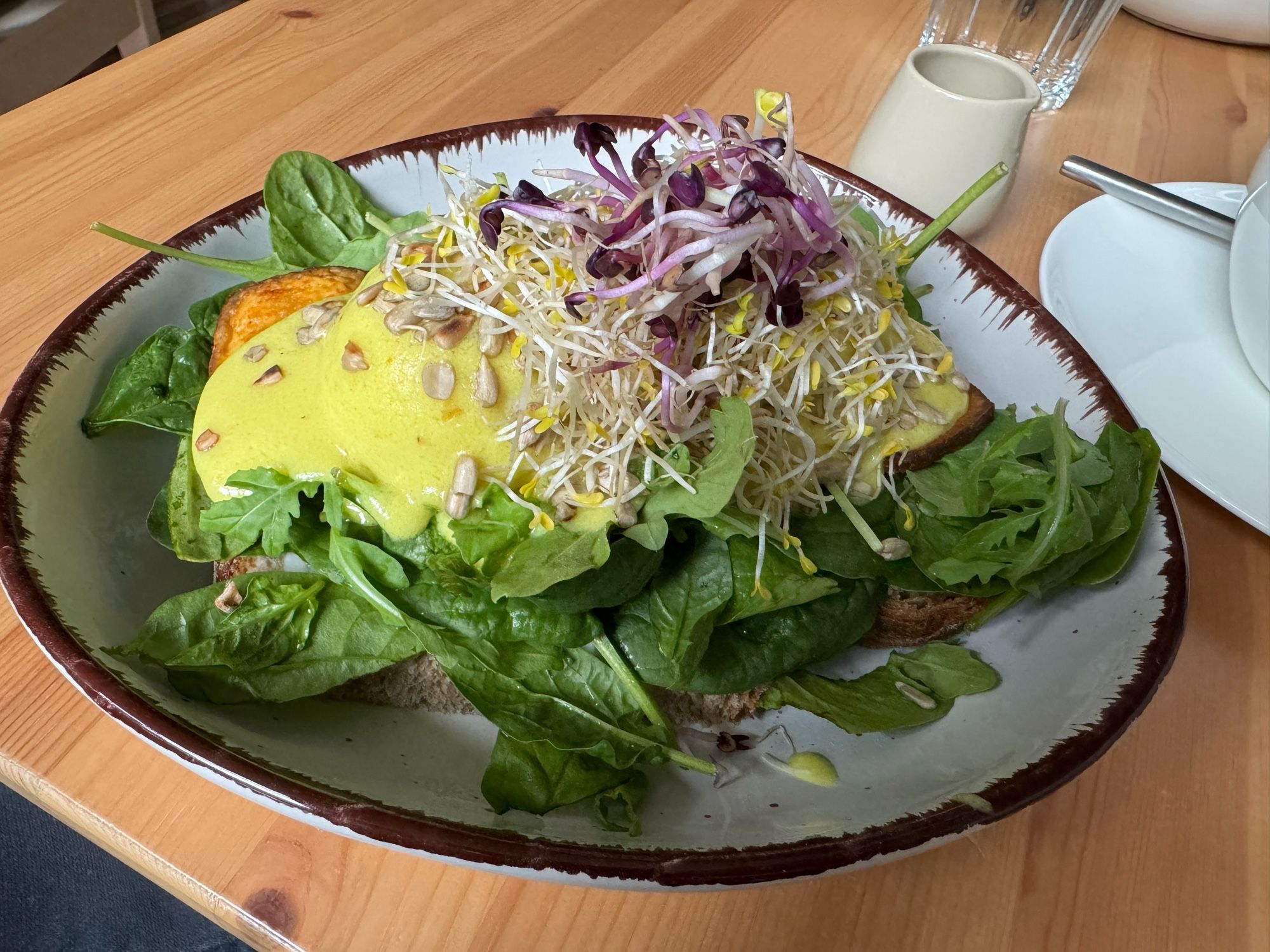 Egg Benedict in vegan mit viel grünem Salat in einem tiefen Teller.