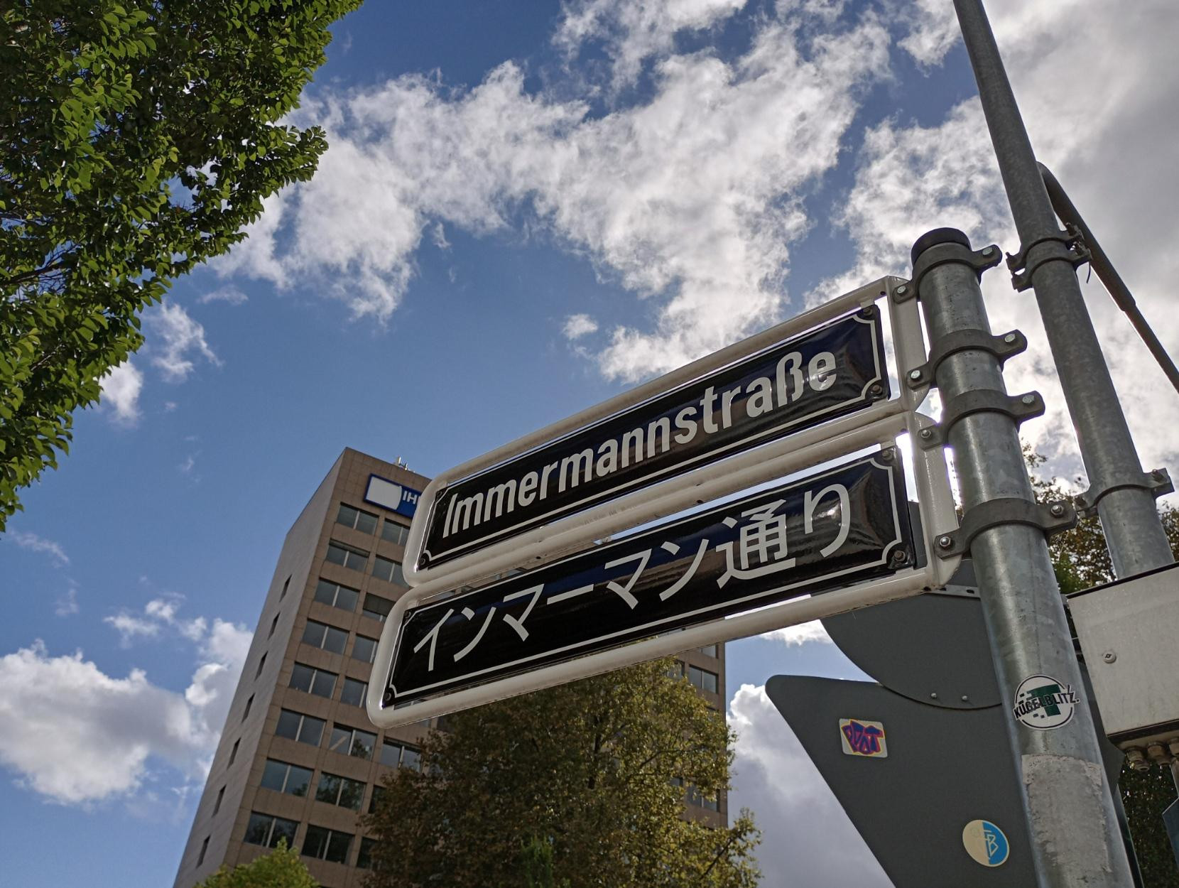 Straßenschild Immermannstr. auf Deutsch und Japanisch, Wetter heiter bis wolkig