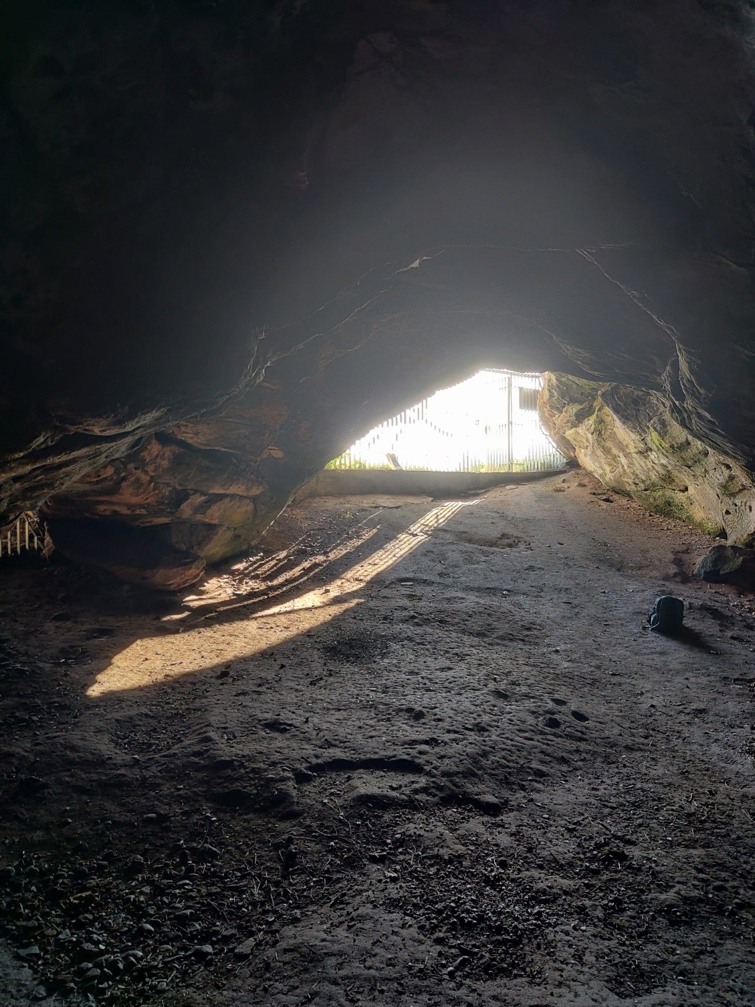 Taken from the inside of a sandstone cave, with sloping ground and sunlight falling in, slanting to the left