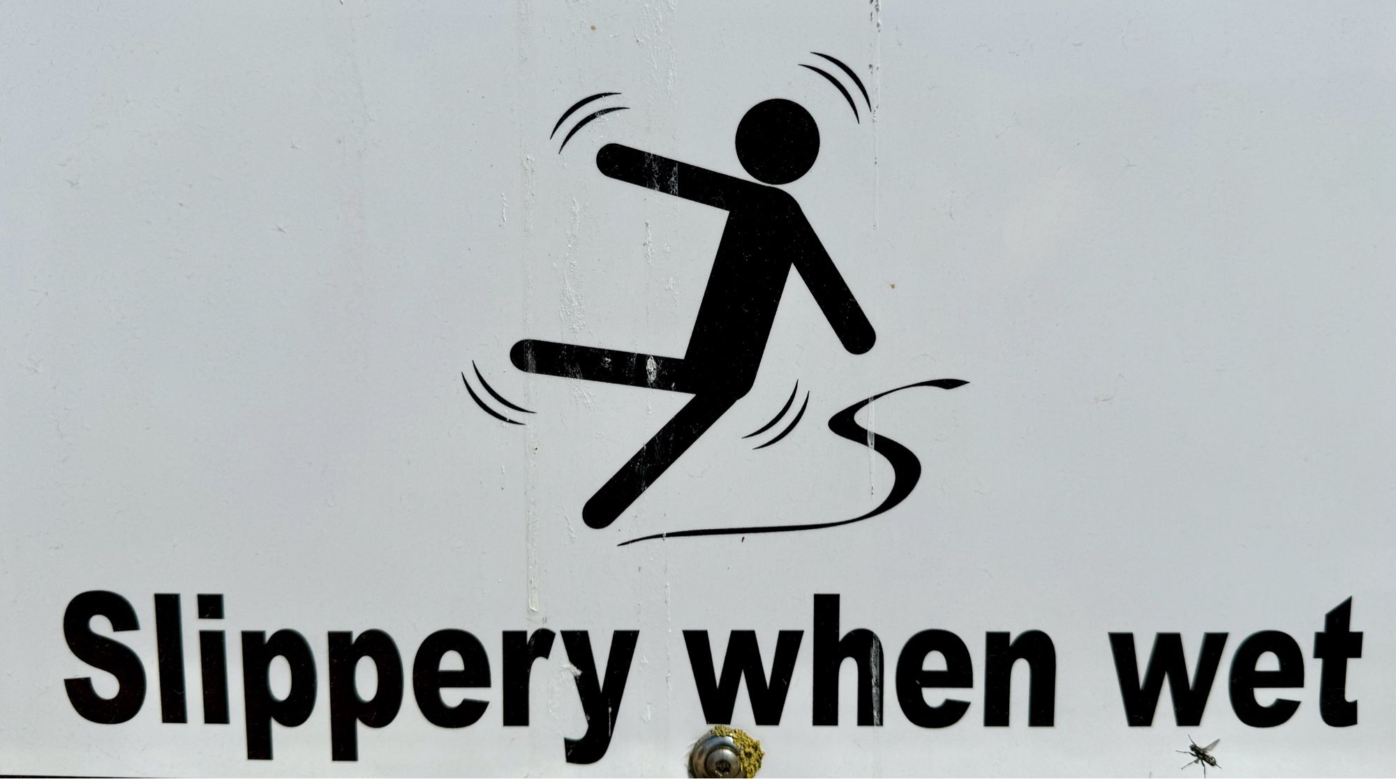 Ein Schild mit einem Menschen als Piktogramm, der ausrutscht, darunter steht: Slippery when wet.