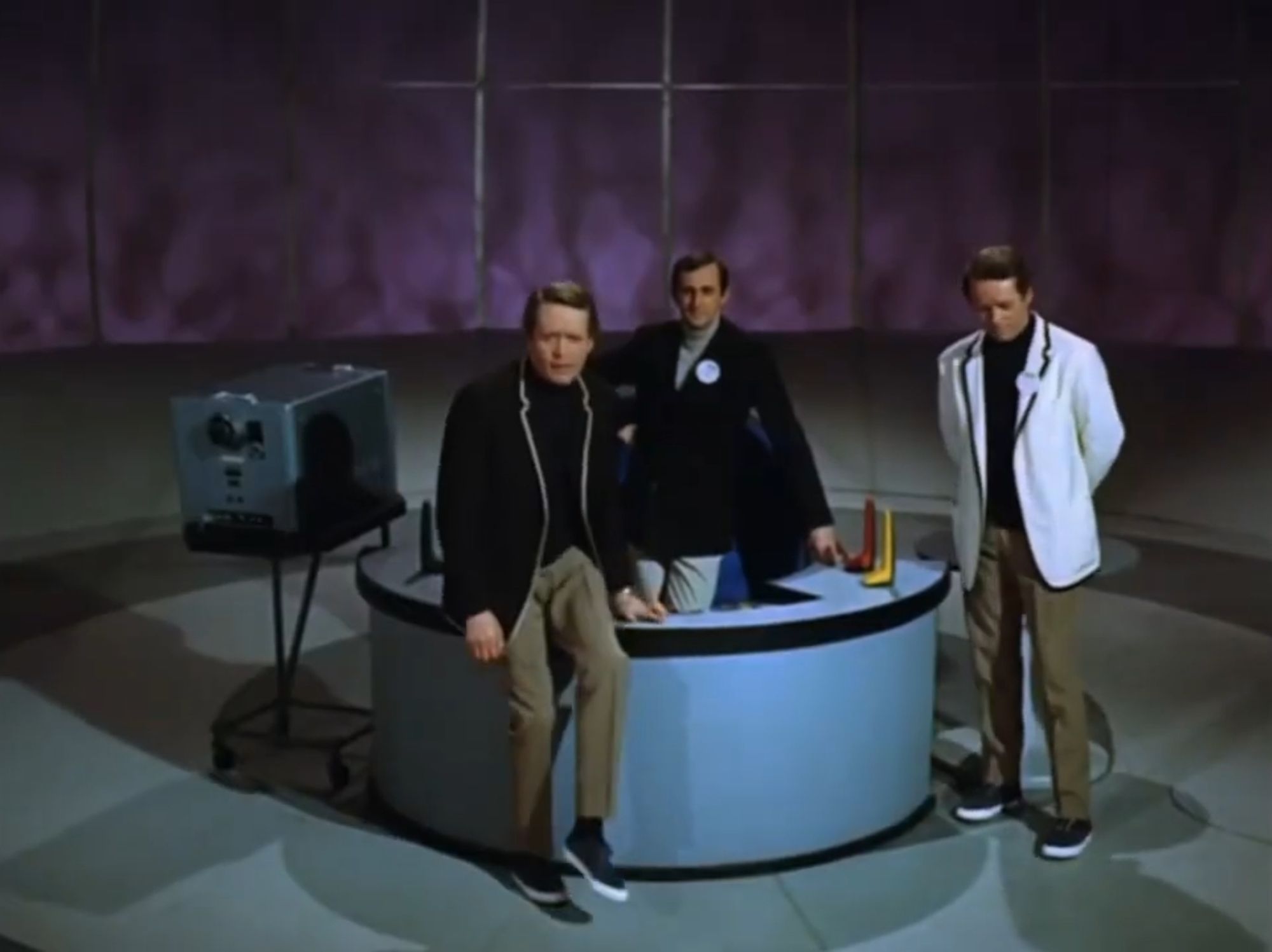 Scene from The Prisoner episode "The Schizoid Man"

Number 2, Number 6 and and imposter Number 6 are in Number 2's office. One of the №6 is wearing a white blazer while the other a black blazer