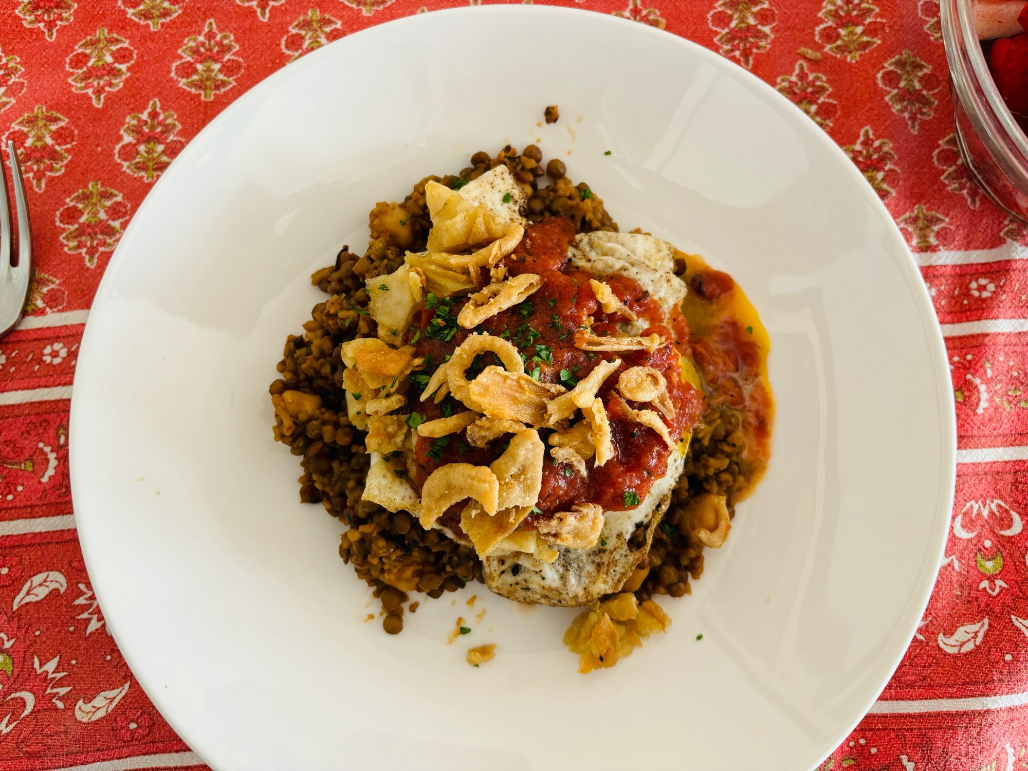 Lentils and rice with chickpeas, topped with noodles, a fried egg, spicy tomato sauce and crispy onions