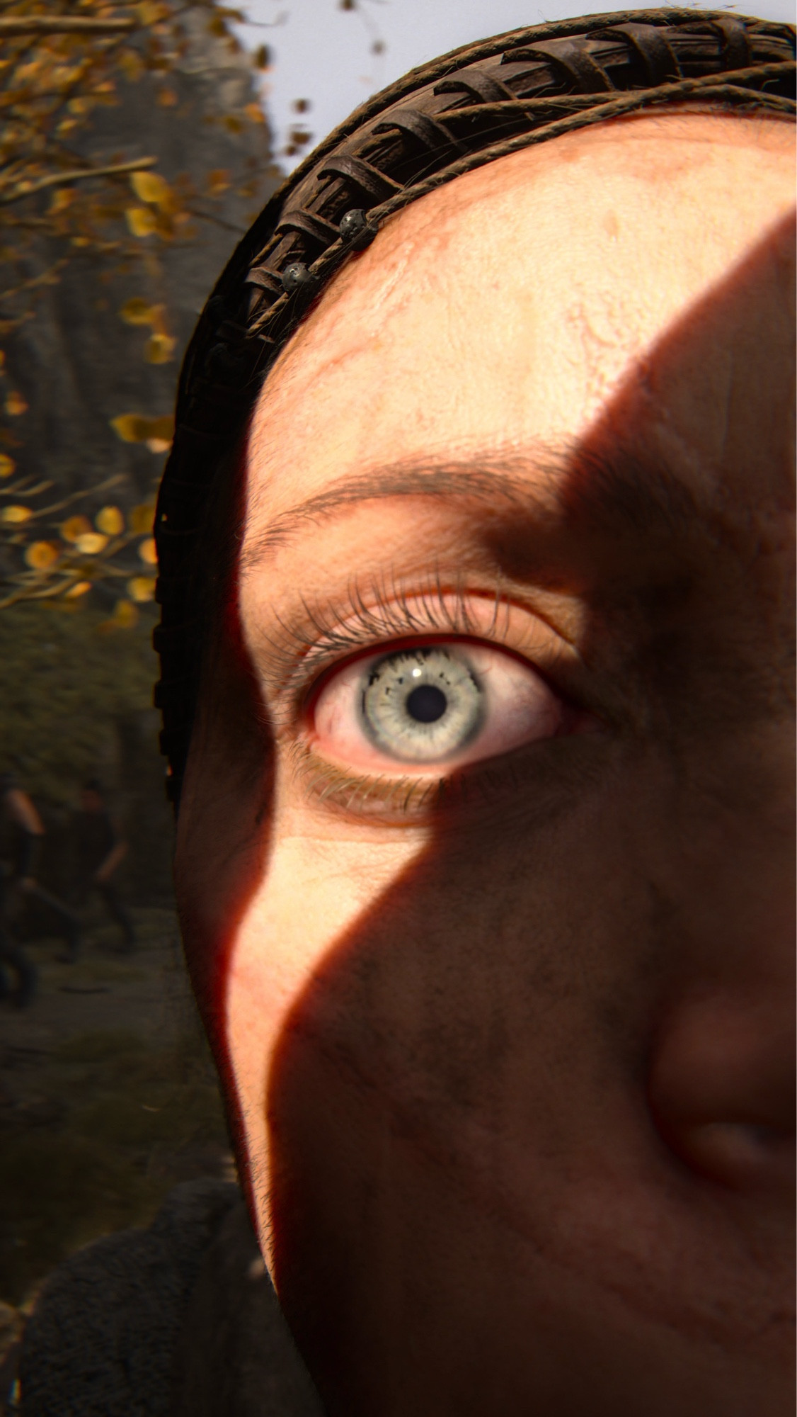 A close up of Senua’s eye in the game Hellblade 2. Her eye is in the light, with shadow falling across the rest of her face