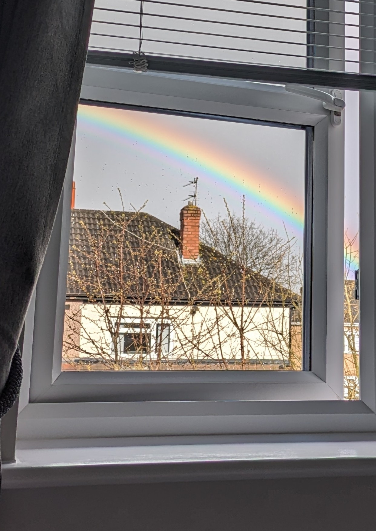 Part of a vivid rainbow, seen through a window