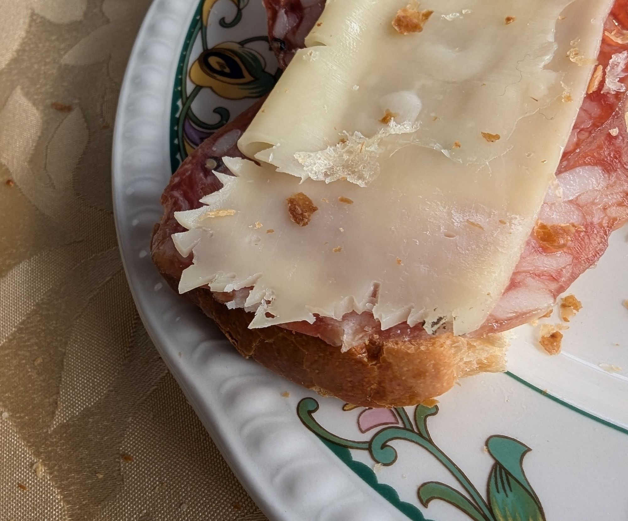 A photo of a piece of bread with a slice of cheese on top. The cheese has dozens of tiny bird bites in it