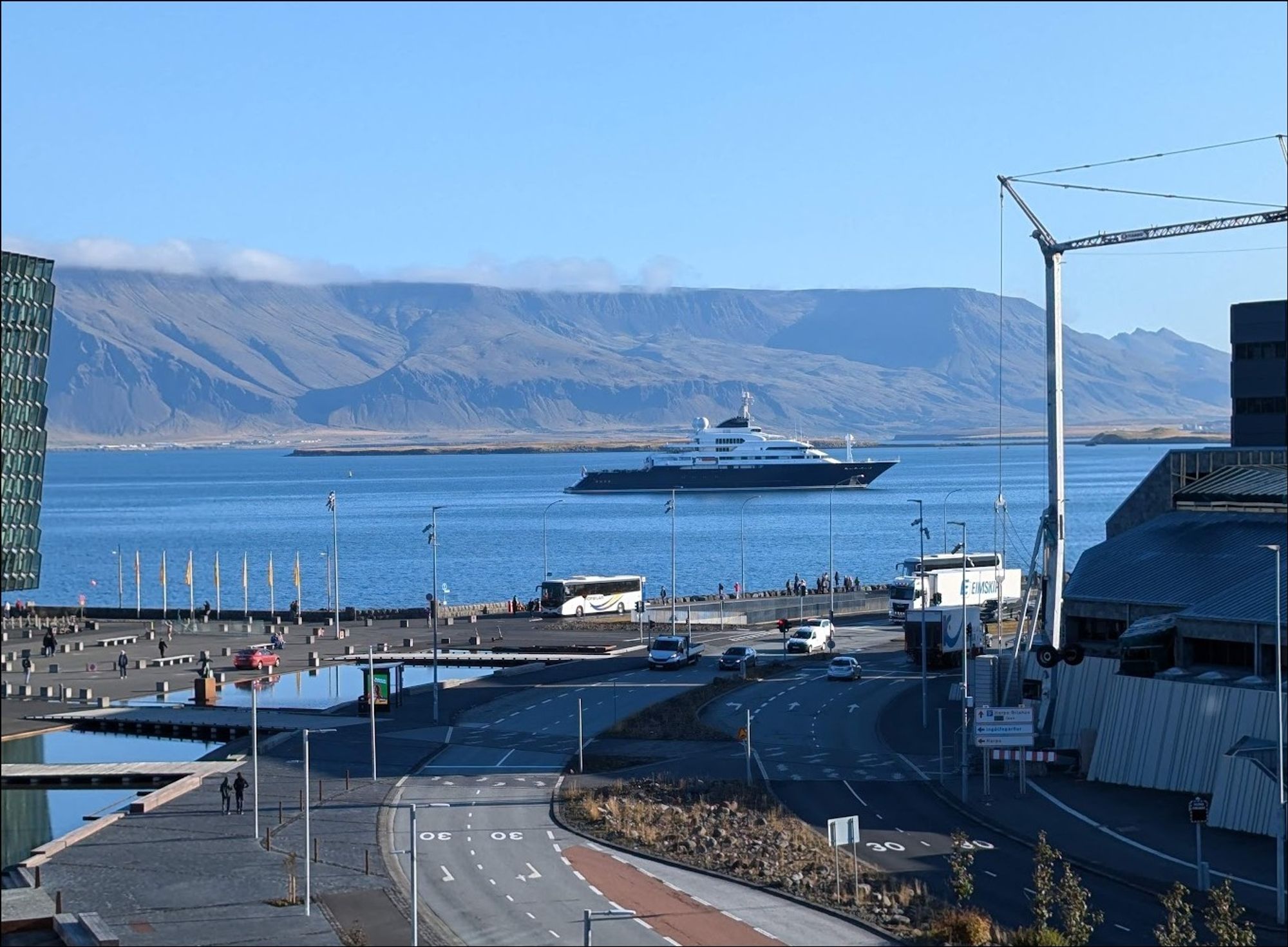 A photo of the superyacht Octopus resting at anchor in Reykjavík. Its immense size can be gauged by how it is many times larger than the passenger buses in the foreground (that are much closer to the camera)