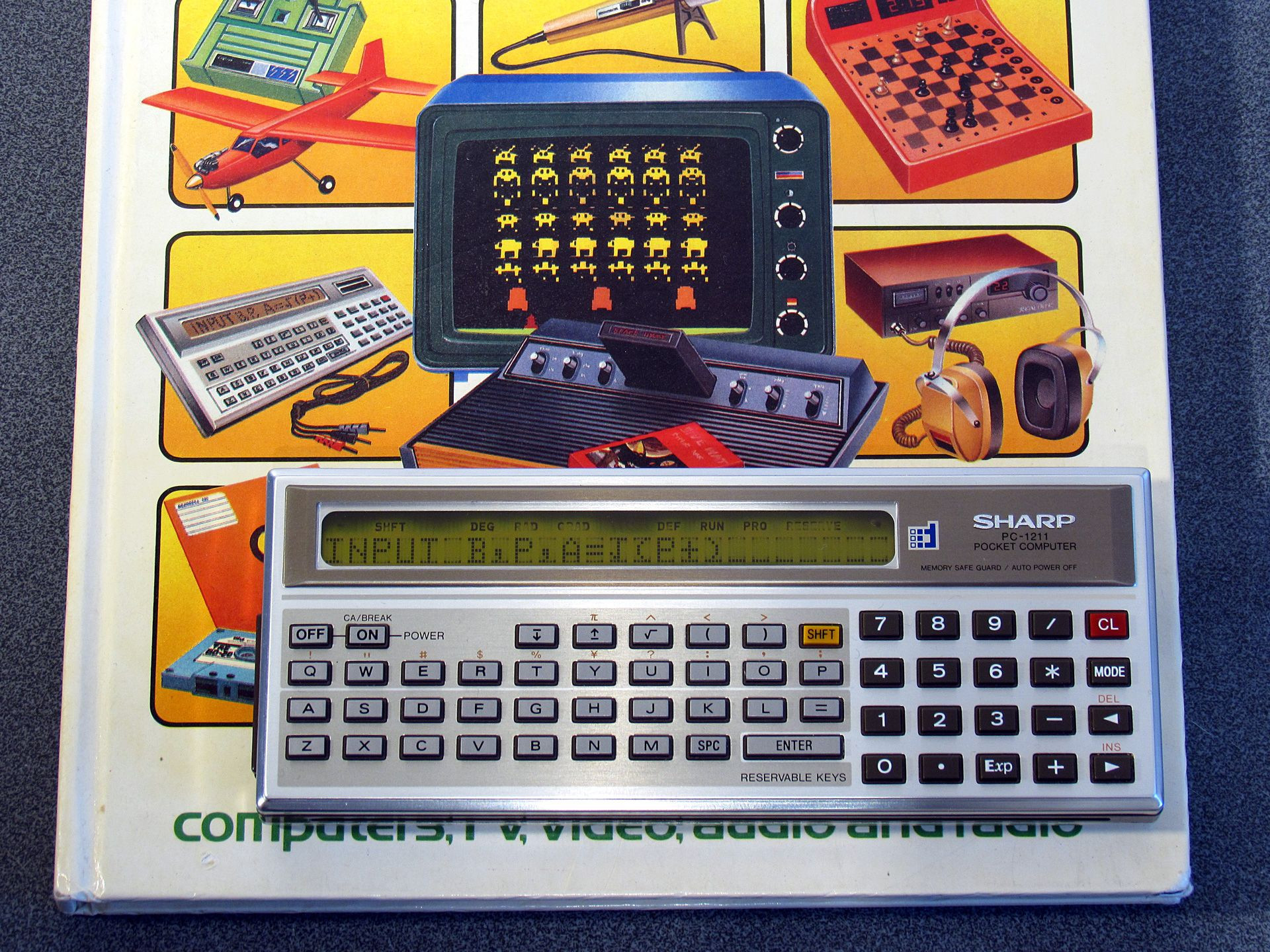 Photo of the cover of Usborne's "World of Electronics" book alongside a Sharp PC-1211.