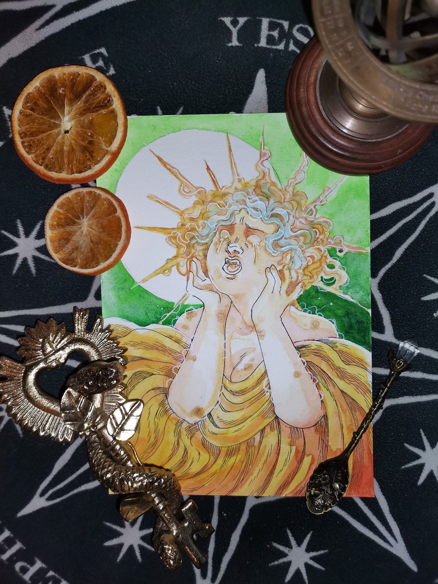 Image surrounded by a golden key with a snake, a spoon, a small celestial globe and two slices of dried orange. The image in the middle shows a person in distress, crying in a yellow dress and sunbeam like-fiery hair.