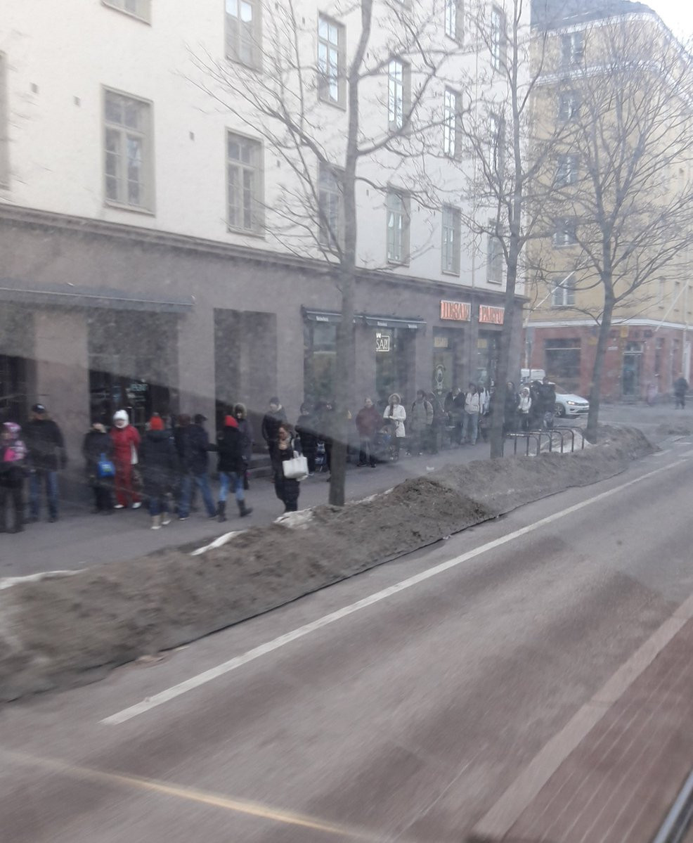 Raitiovaunun sisältä otettu kuva ihmisistä jonottamassa ruoka-apua Helsinginkadulla.