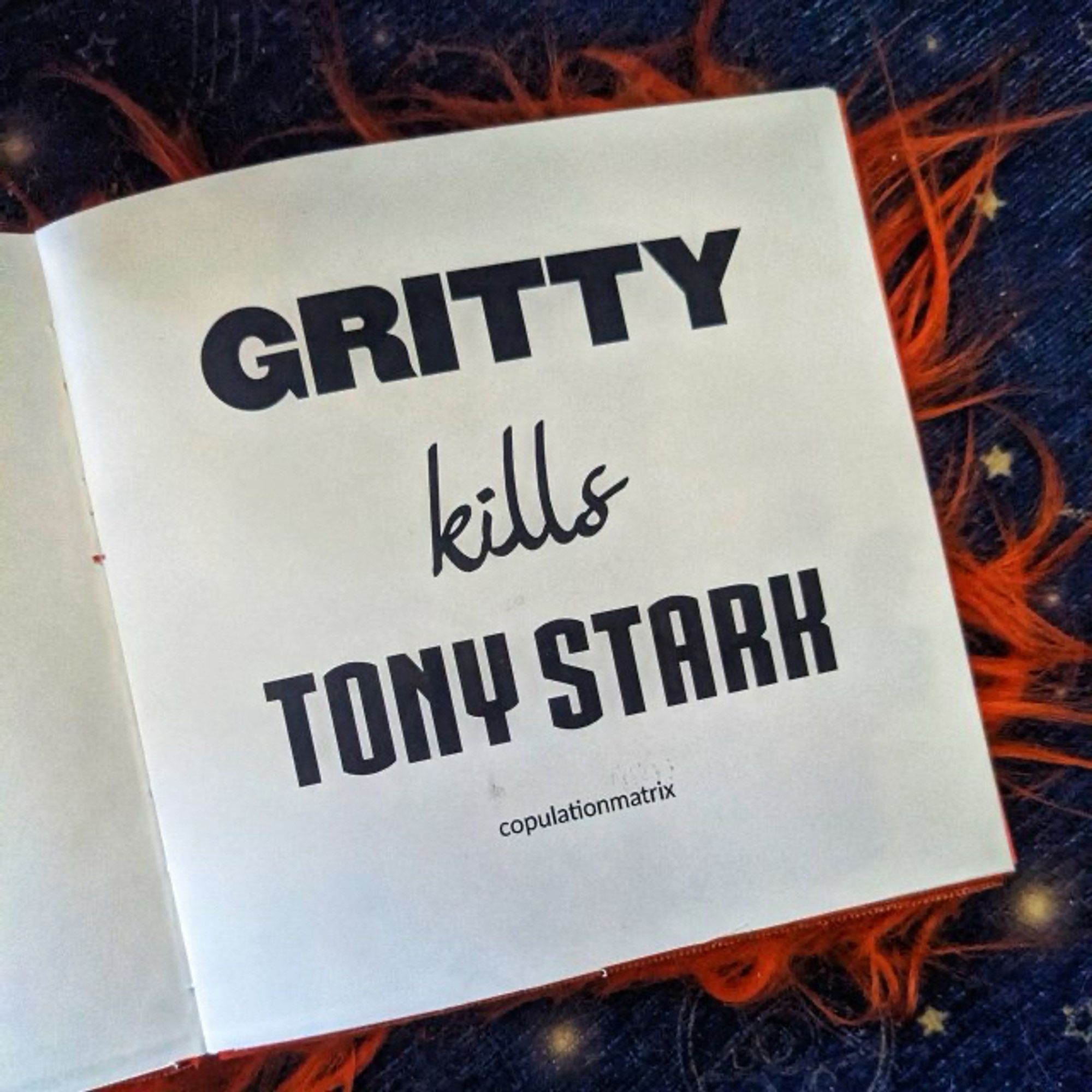 The title page of the fuzzy orange book! The page is white, square, snd says “Gritty kills Tony Stark” in fancy fonts.