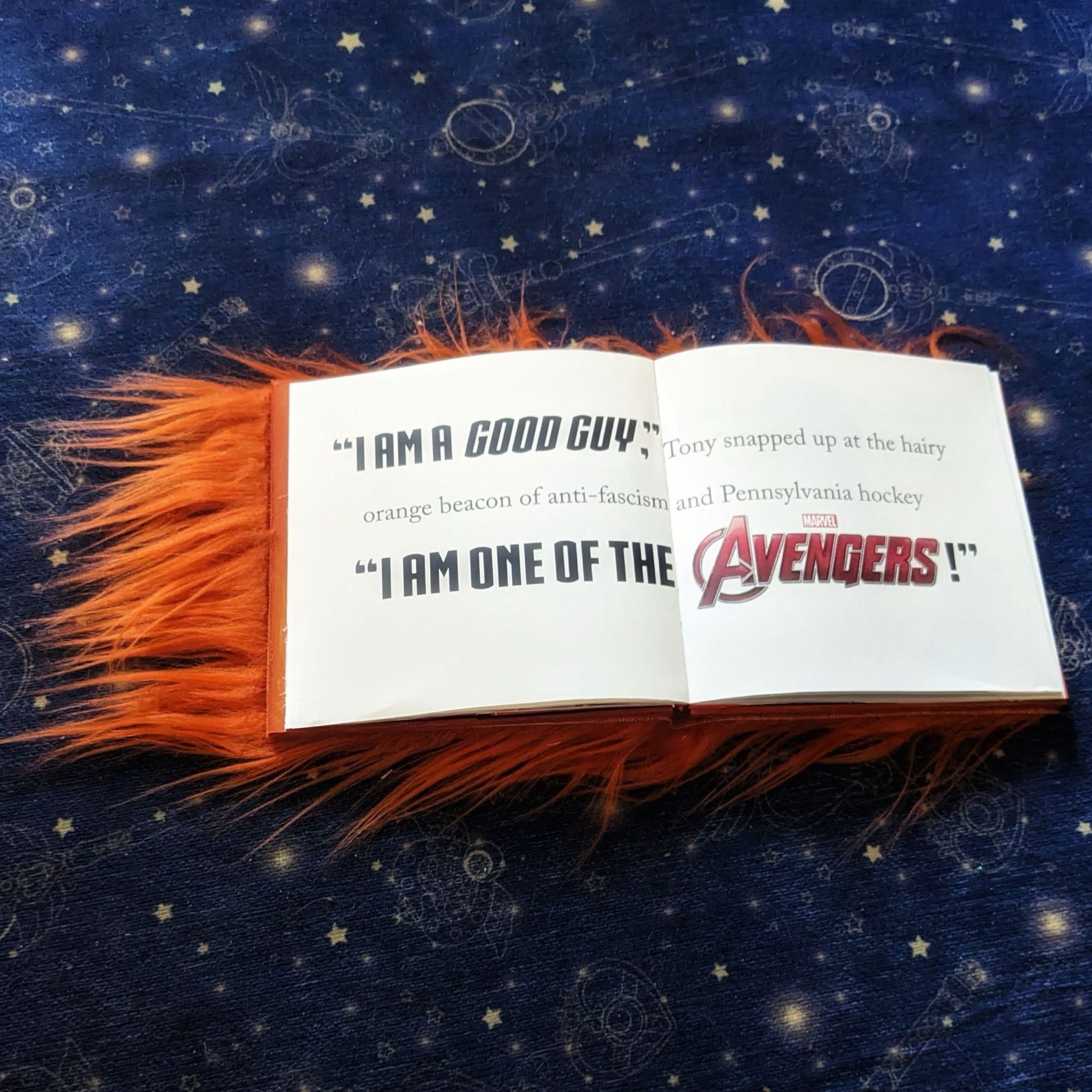 The fuzzy orange book is open to a spread, where artfully designed text says “I am a good guy,” Tony snapped up at the hairy orange beacon of anti-fascism and Pennsylvania hockey. “I am one of the Avengers!”