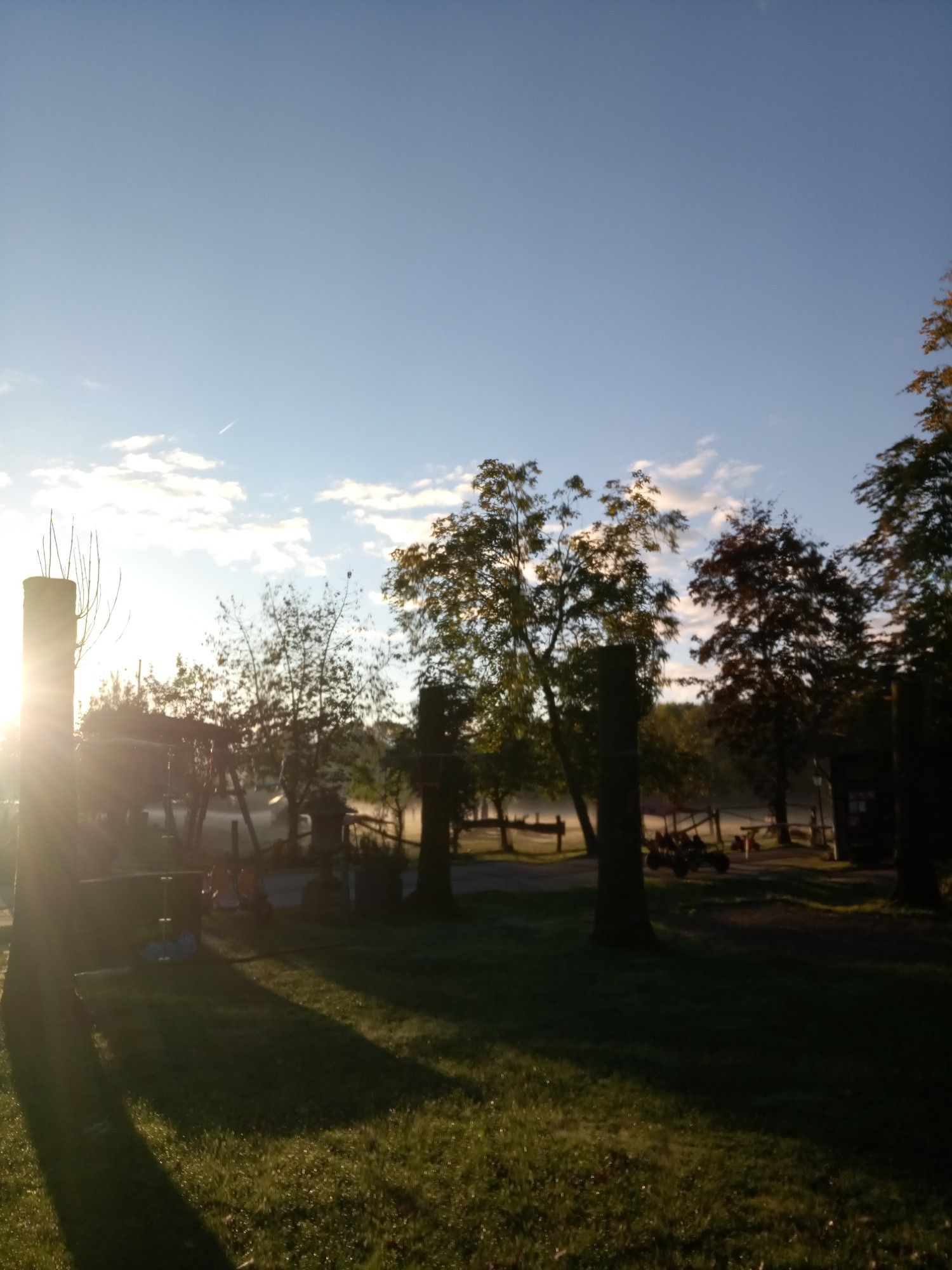 Morgensonne über Wiese mit blauem Himmel und kleinen Wolken