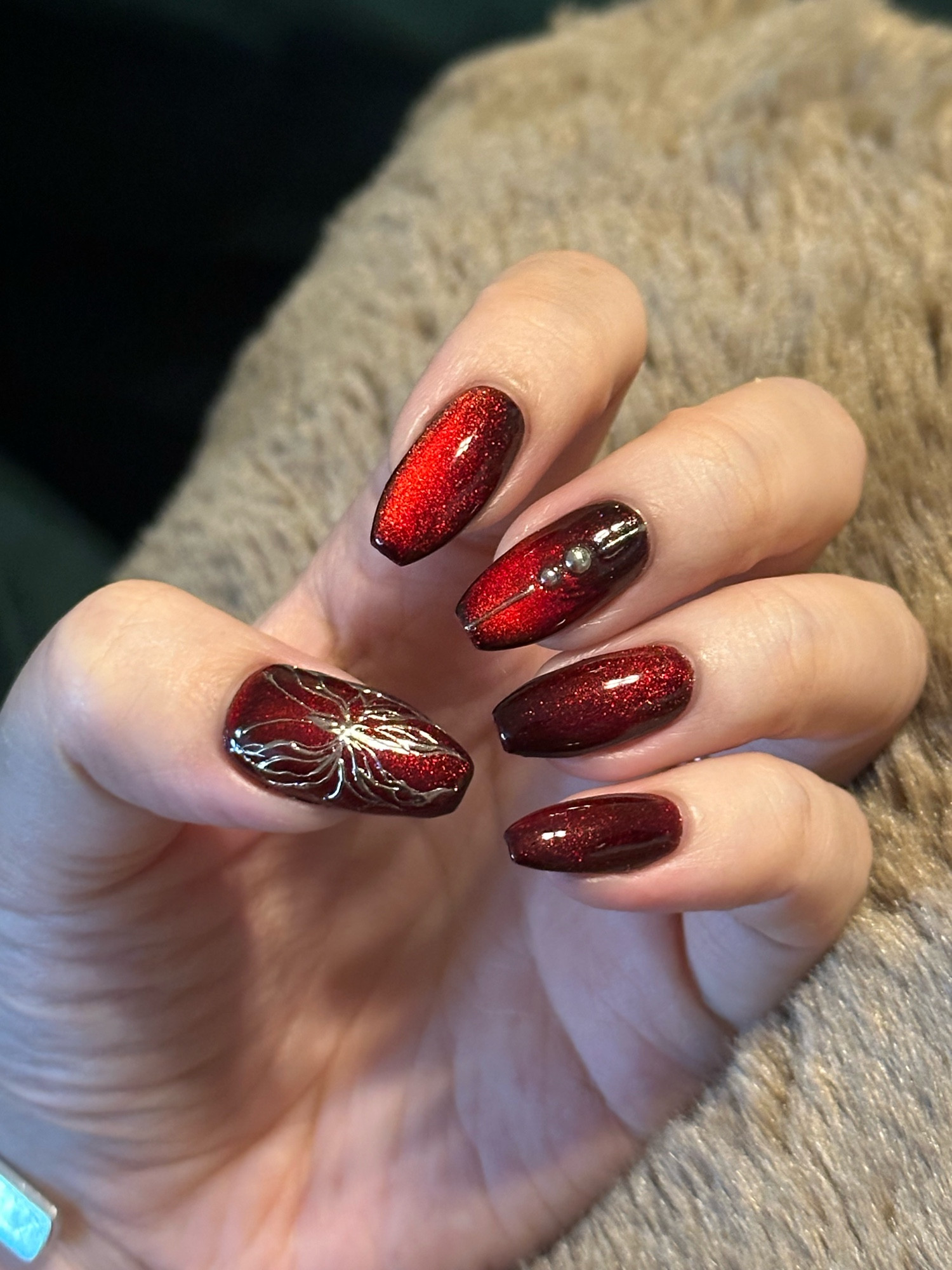 Red nails with a sparkly magnetic effect and silver butterfly nail art. 