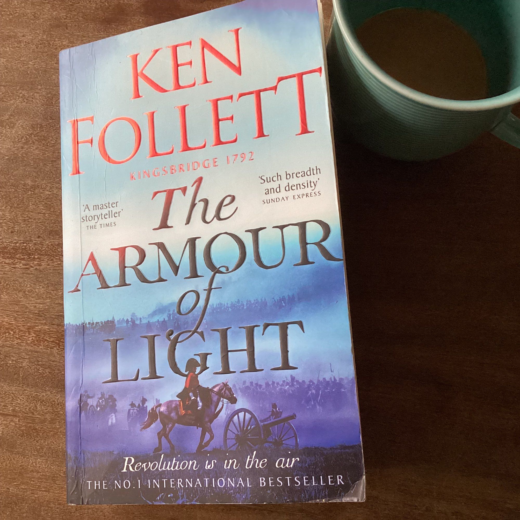 Buch mit Titel: Ken Follet. The Armour of Light. Kingsbridge 1792.
Buch mit blauem Umschlag. Eine historische Kriegsszene mit britischen Soldaten und Kanonen im Nebel ist zu sehen.