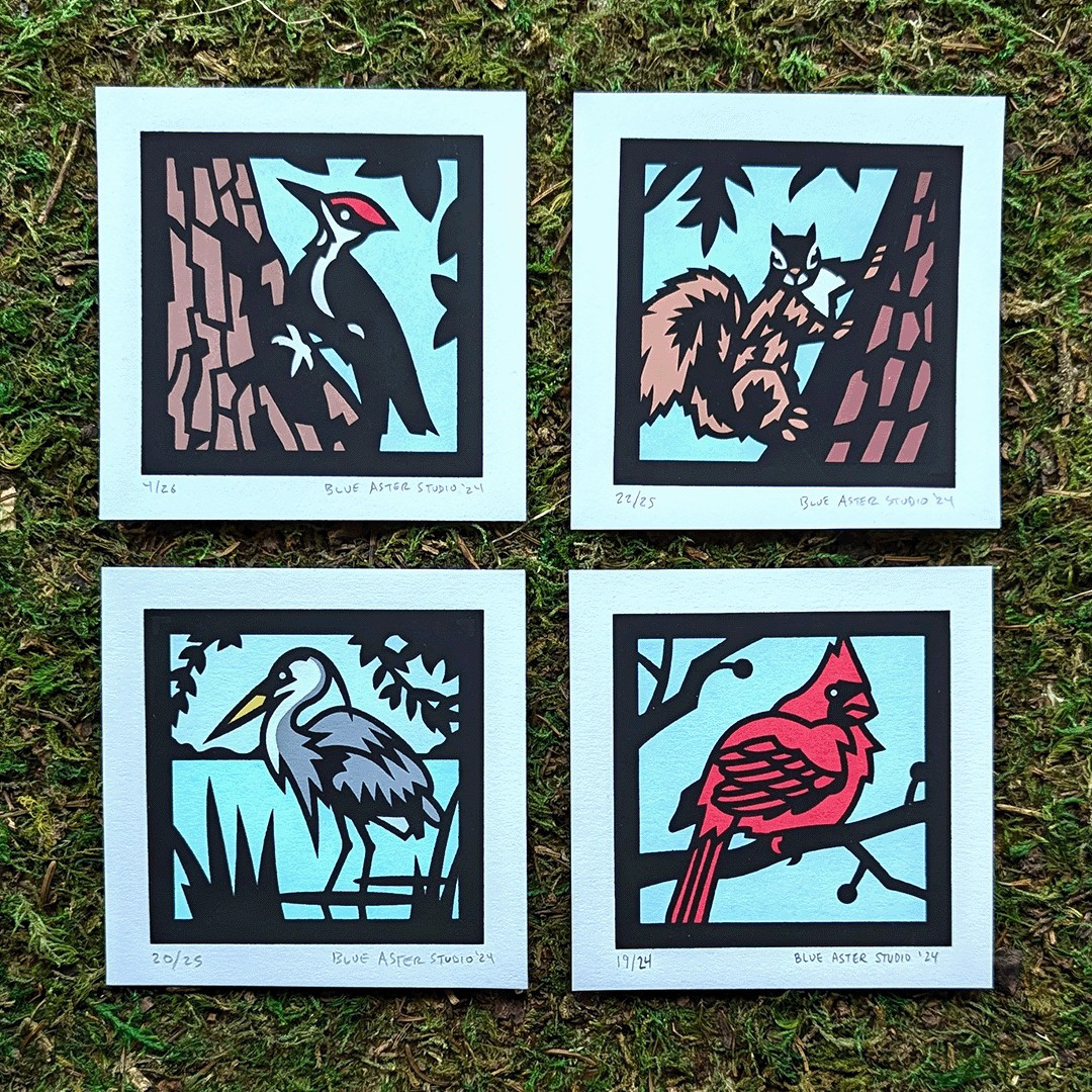 A set of four inch wildlife screen prints, including a pileated woodpecker, squirrel, great blue heron, and cardinal 