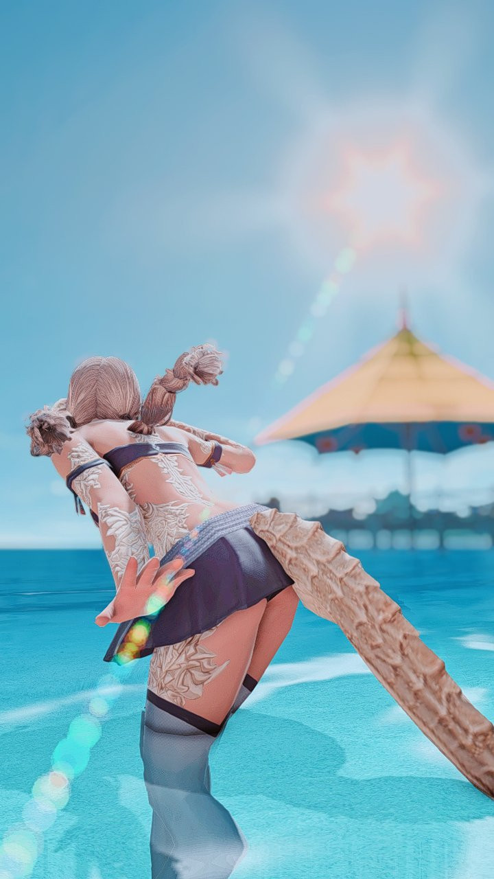 A back shot of Mana standing in the water, looking out further into the sea. There is a bright lens flare from the sun in the sky. The docks with a wide umbrella is in the background, out of focus. 