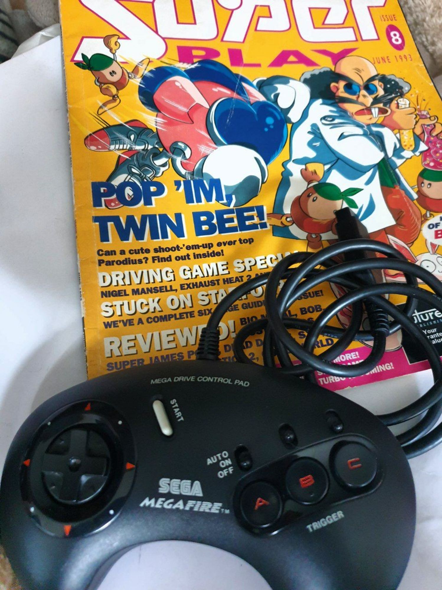 A photo of the Sega Megafire 3 button controller (It's an official one from Sega with turbo switches) and issue 8 of Superplay with Pop 'n' TwinBee as the cover artwork and one of the features.