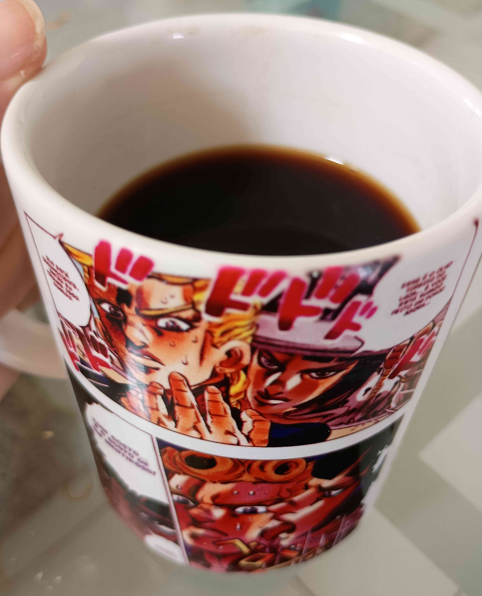 Imagem de xícara de café com estampa da HQ de Jojo mostrando interação de Bruno e Giorno, no qual ele o lambe durante o interrogatório e afirma que tem gosto de mentira.