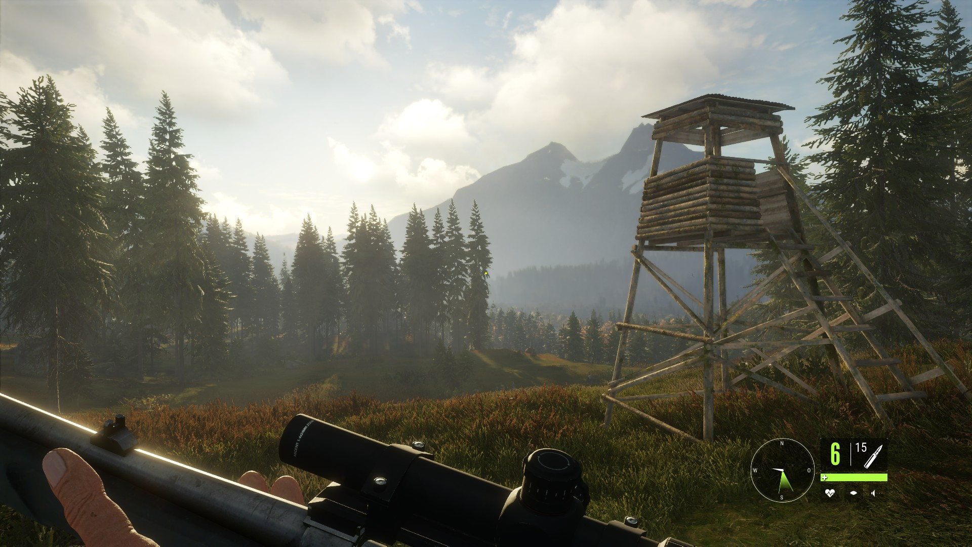 Ein wunderschönes Wald-Berg-Panorama im Spiel "The Hunter: Call of the Wild". Rechts ein Hochsitz. Der Spieler hält ein Kleinkalibergewehr einsatzbereit.