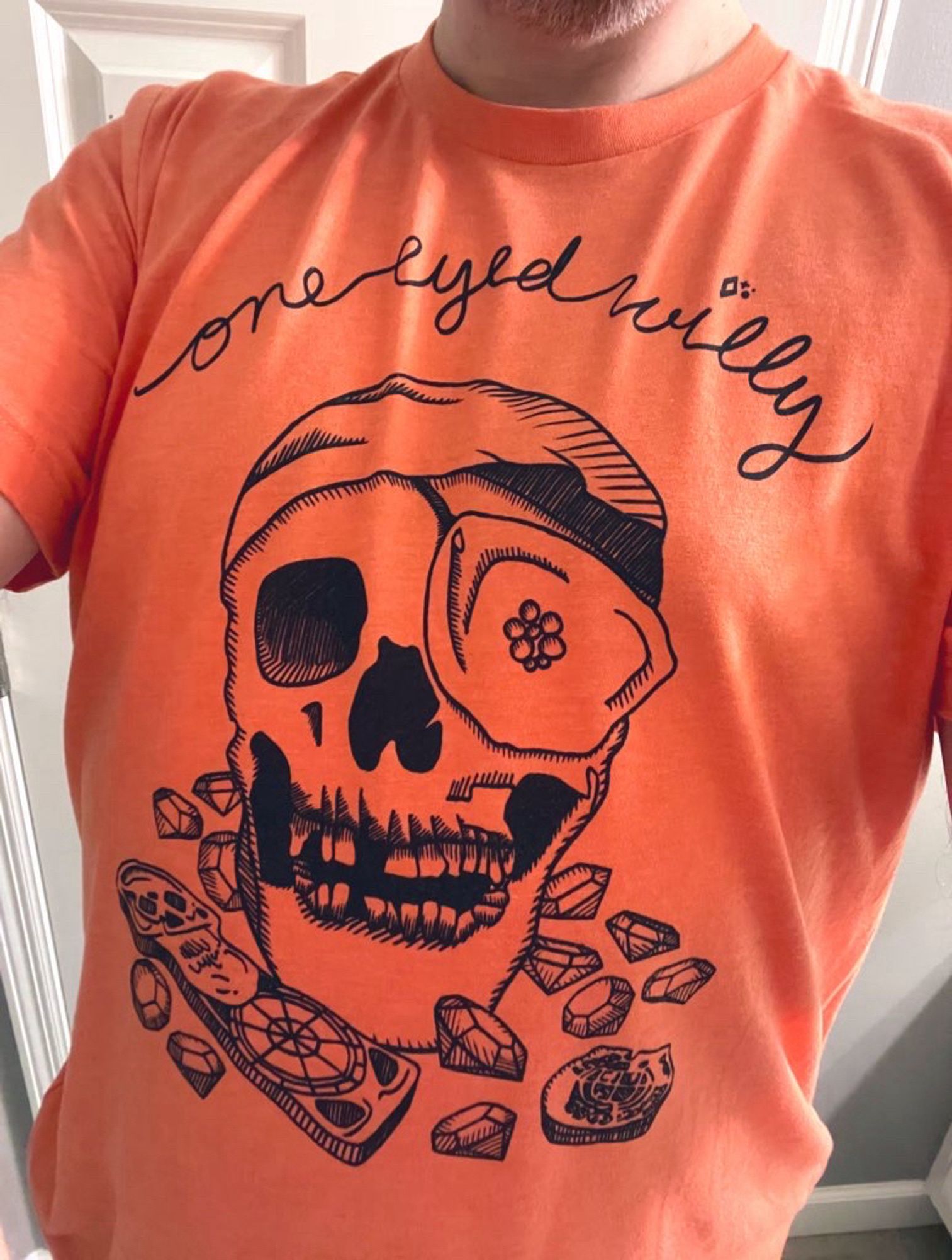 Orange shirt with skull pirate image on it with text that says “one eyed Willy”