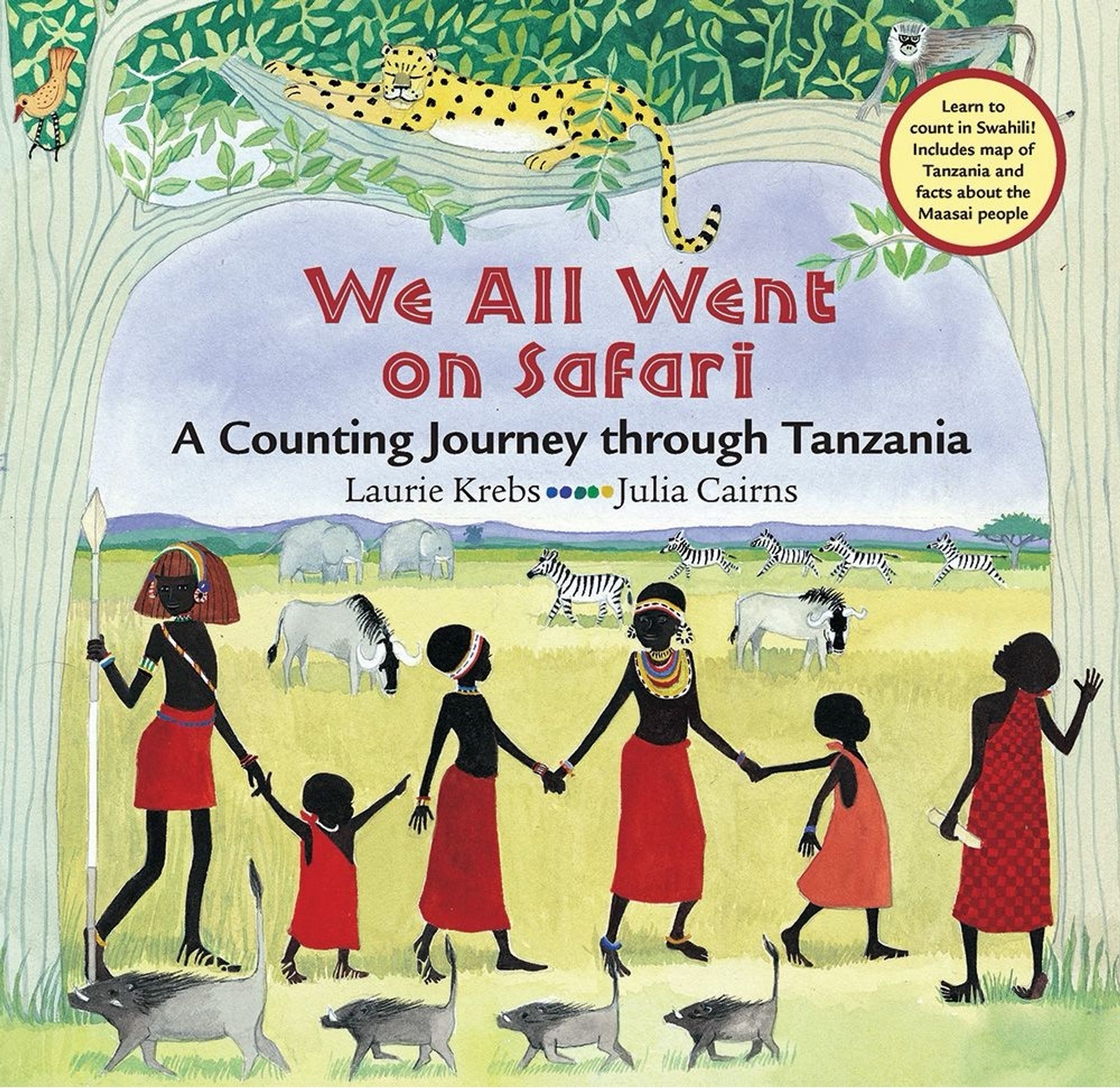 Front cover of picturebook called We All Went On Safari. A counting journey through Tanzania by Laura Krebs and Julia Cairns. Illustration with six people from the Masai tribe in traditional dress, holding hands and walking in a line from left to right. In the foreground a line of four warthogs walk in front of them from right to left. In the background zebras, wildebeest and elephants graze on the Tanzanian savannah. Above them a leopard, a monkey and a bird are in the branches of two trees, one at each side of the cover.