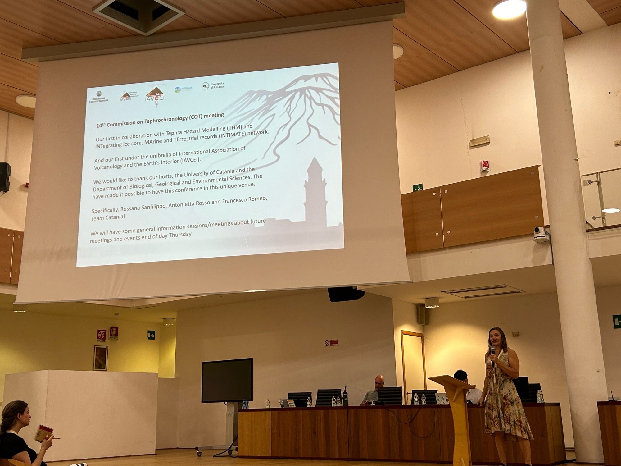 Britta Jensen introducing the meeting on a stage in a lecture theatre.