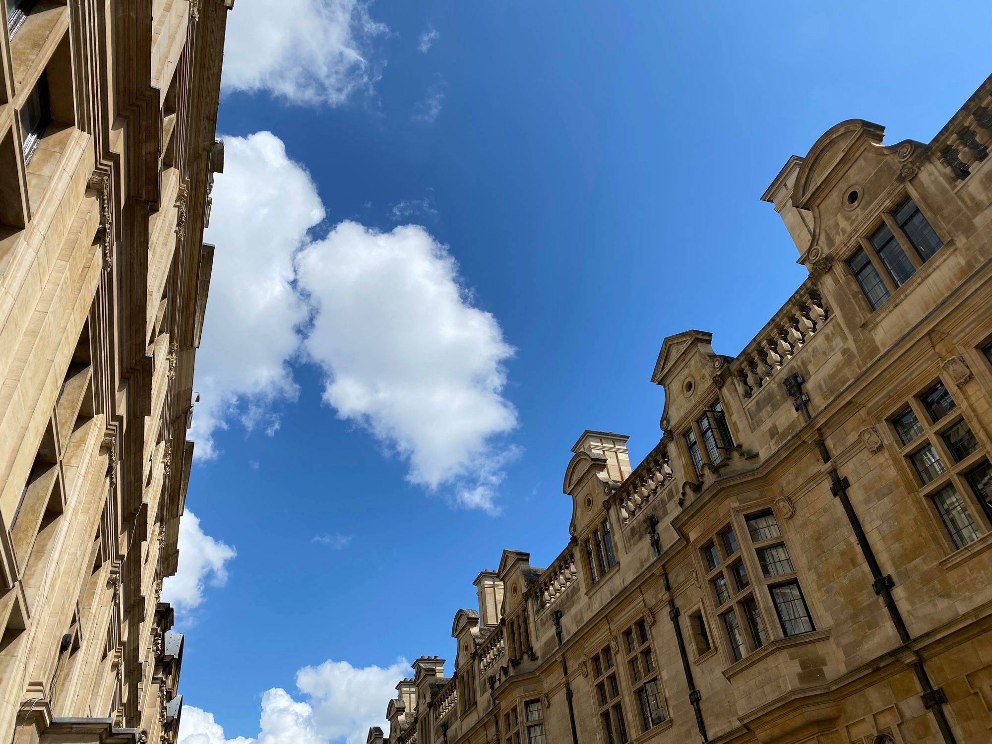 Blue sky viewed between sandstone college buildings.