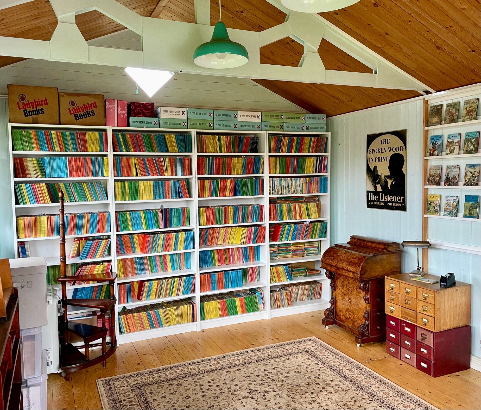 Photograph of a large, airy studio, furnished with one wall completely filled with Ladybird books and assorted library furniture