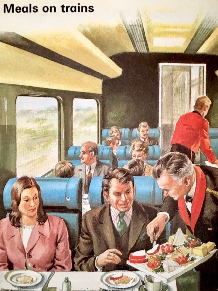 To waiters in formal livery, serve a couple in a train compartment. The meal  and service look like fine-dining.