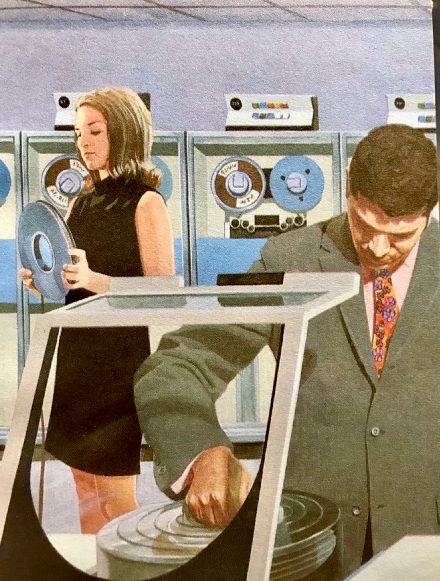 A sharply dressed man and woman in a computing room, doing stuff with large magnetic tape reels