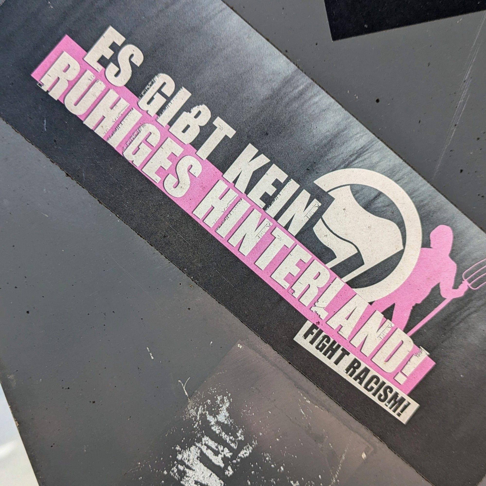 Foto von einem Aufkleber: Es gibt kein ruhiges Hinterland. Fight Racism!