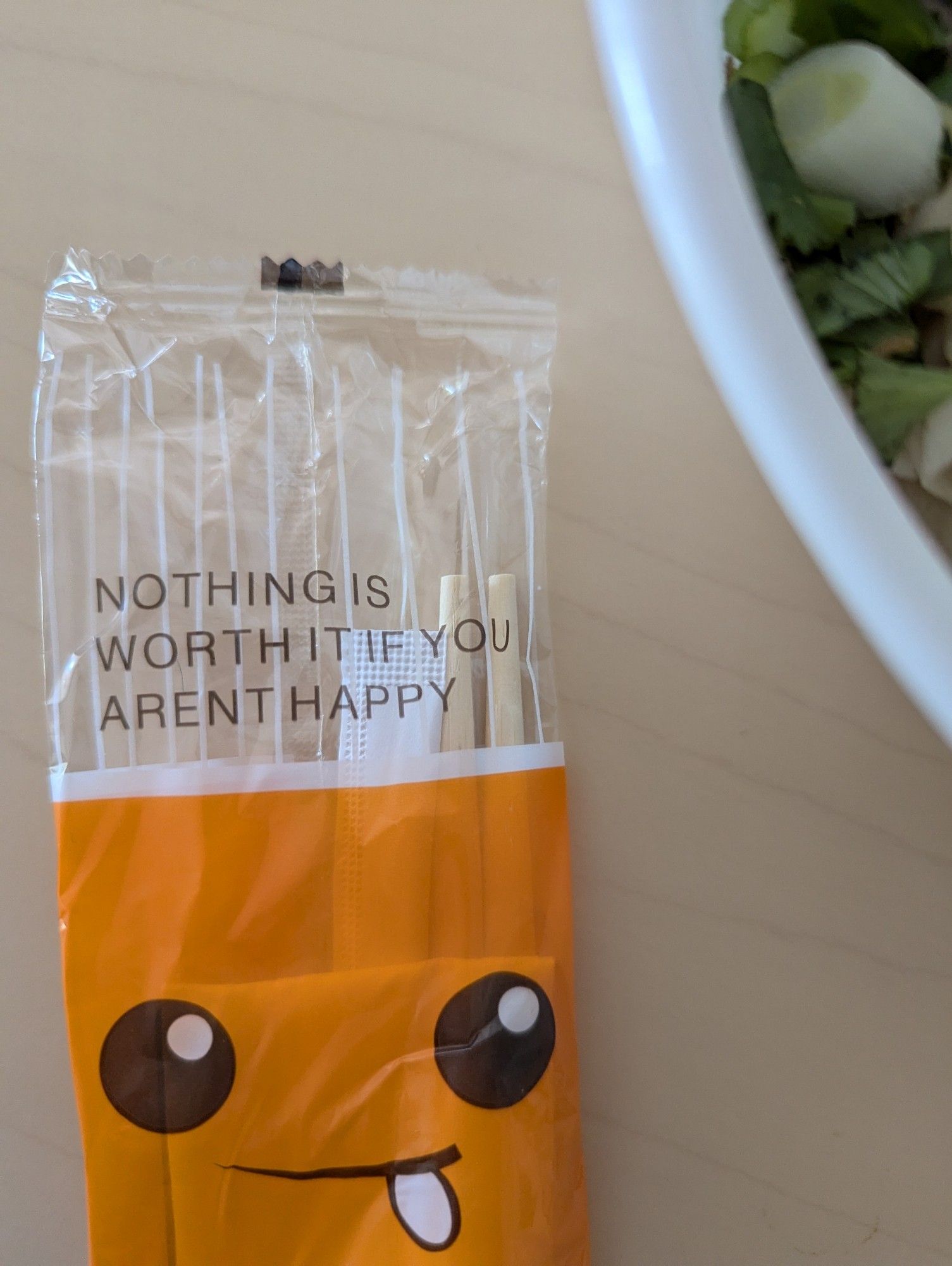 Plastic baggie containing chopsticks and a spork with a 😋 face and the text "nothing is worth it if you aren't happy". Damn right it isn't