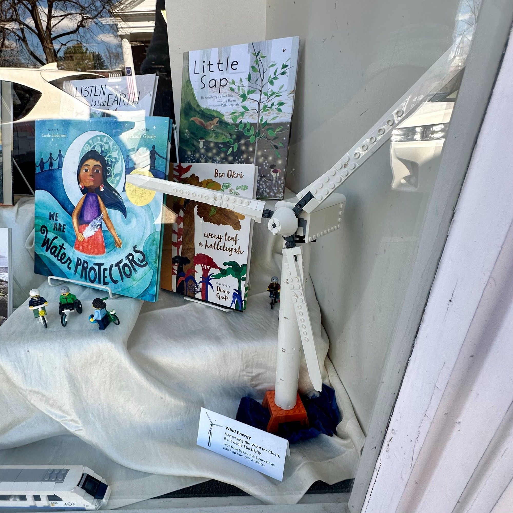 Lego wind turbine, with children's books in the background, including "We Are Water Protectors," "Little Sap," and "Every Leaf a Hallelujah"