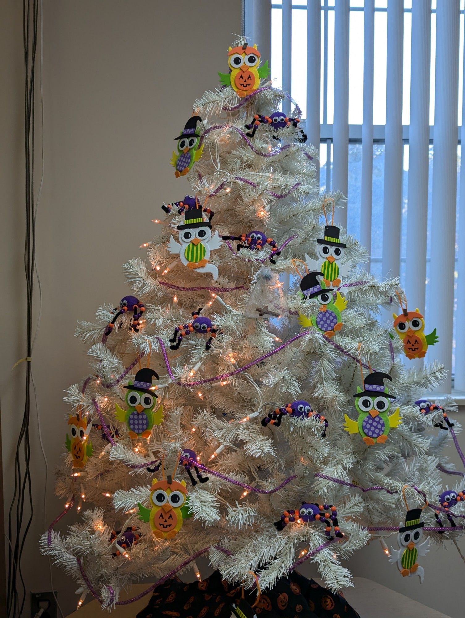 A holiday tree decorated with Halloween owls and spiders 